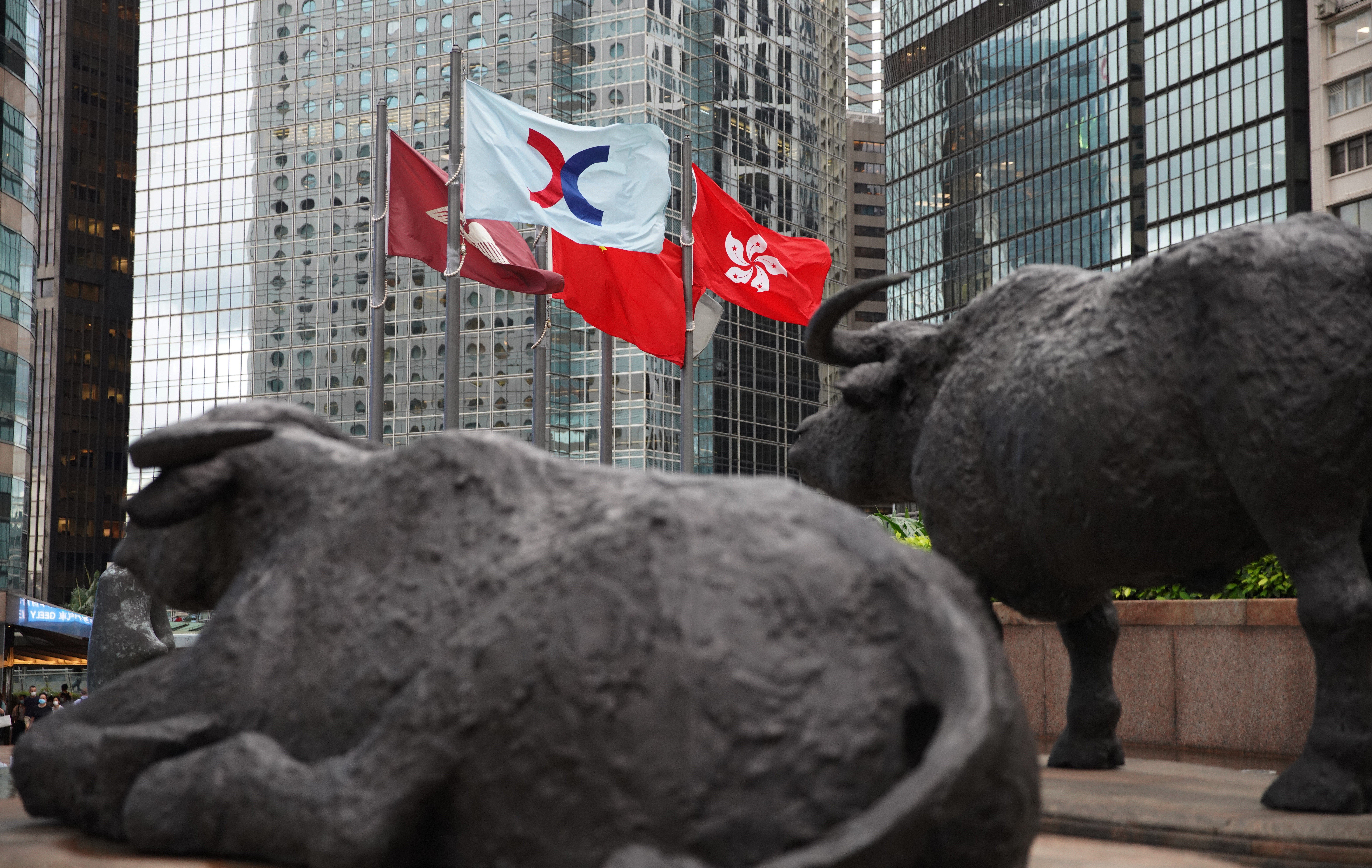The Hong Kong flag and that of the Hong Kong stock exchange fly near bronze sculptures of bulls at the Exchange Square in Central on June 2. The return of bull markets and positive consumer sentiment will be crucial to Hong Kong’s economic recovery from its current woes. Photo: Winson Wong