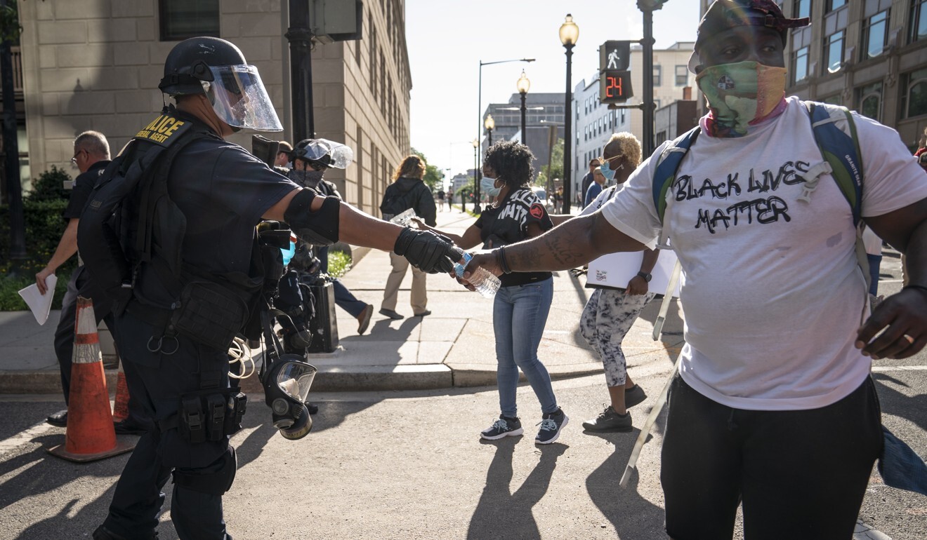 A police officer in riot gear hands out water bottles to protesters near the US Capitol, in Washington. Photo: EPA