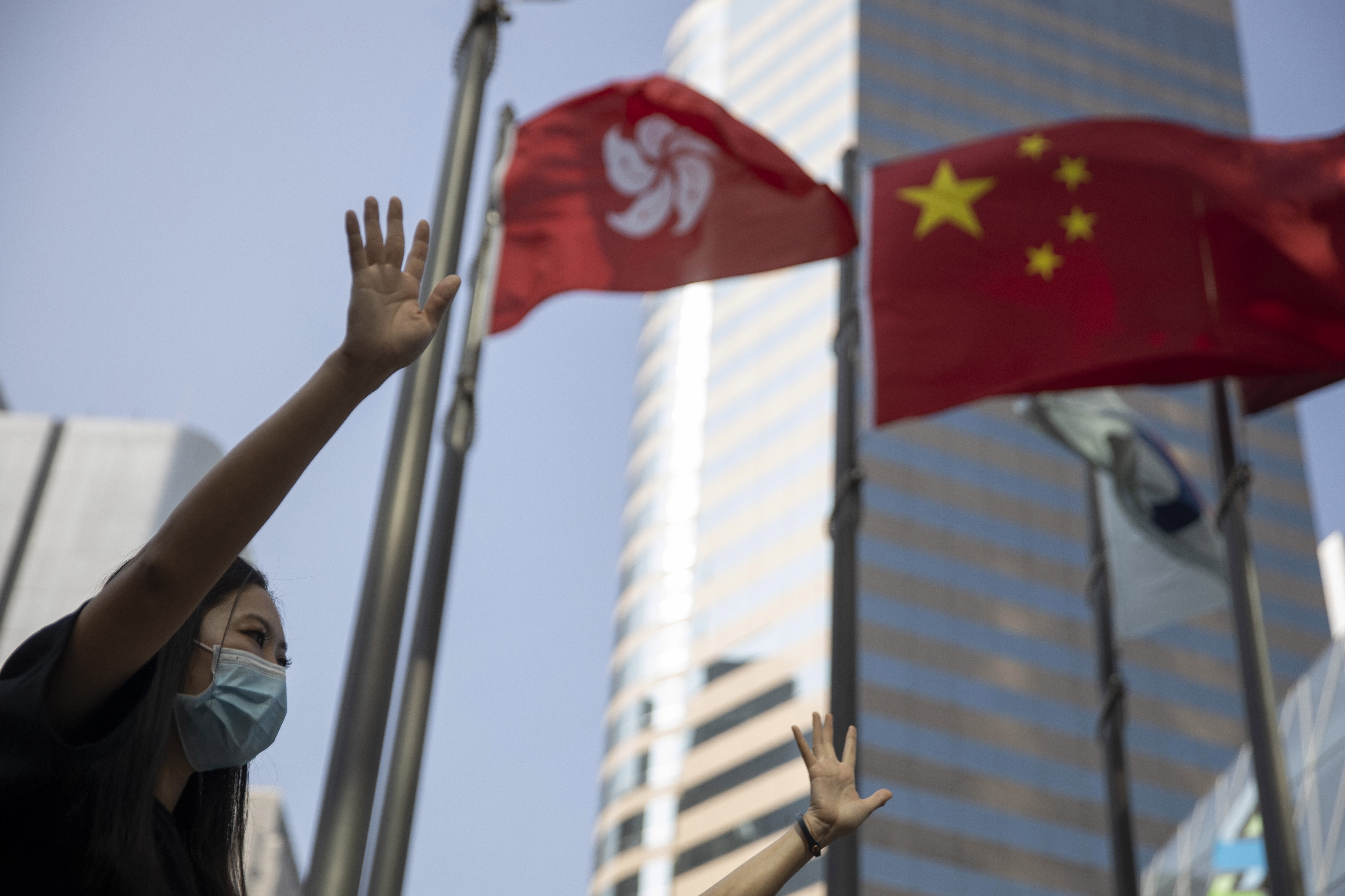Protesters hold up their hands to represent their five demands near the Hong Kong and Chinese flags at Exchange Square in Central on November 15, 2019. The protests have gathered steam again after the National People’s Congress announced it would introduce a national security law for Hong Kong. Photo: AP