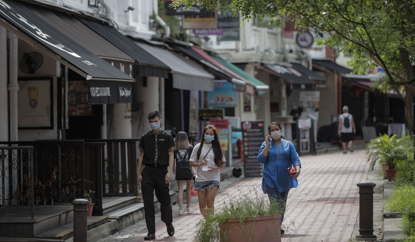 Pedestrians wearing masks walk past shops in Singapore last month. Photo: EPA