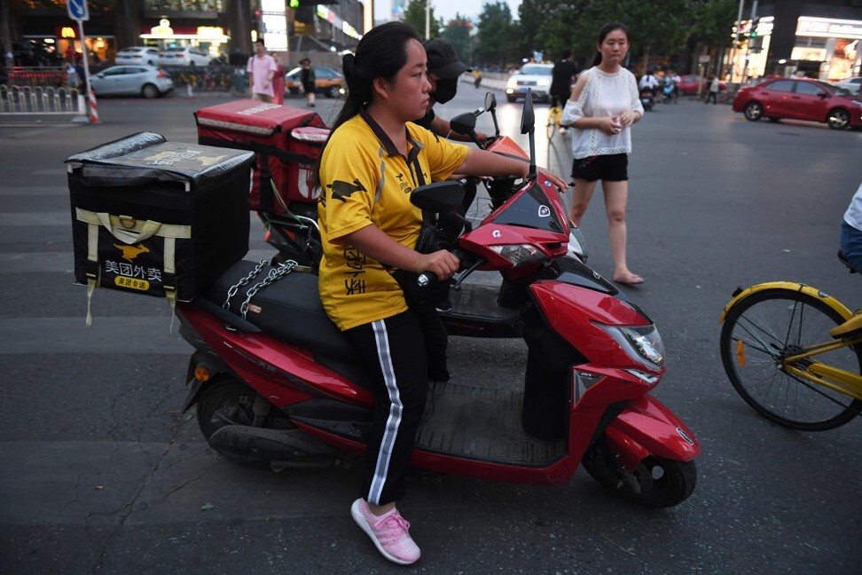 A Meituan delivery rider waits at an intersection as she delivers food in Beijing. Photo: AFP