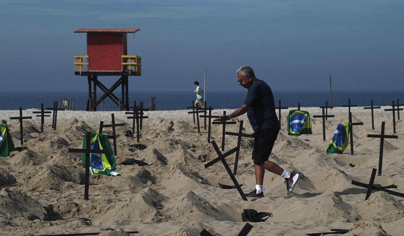 A pro-government man knocks over one of 100 crosses placed by activists from the Brazilian NGO Rio de Paz (Peace Rio), symbolising deaths from Covid-19 in Rio de Janeiro. Photo: AFP