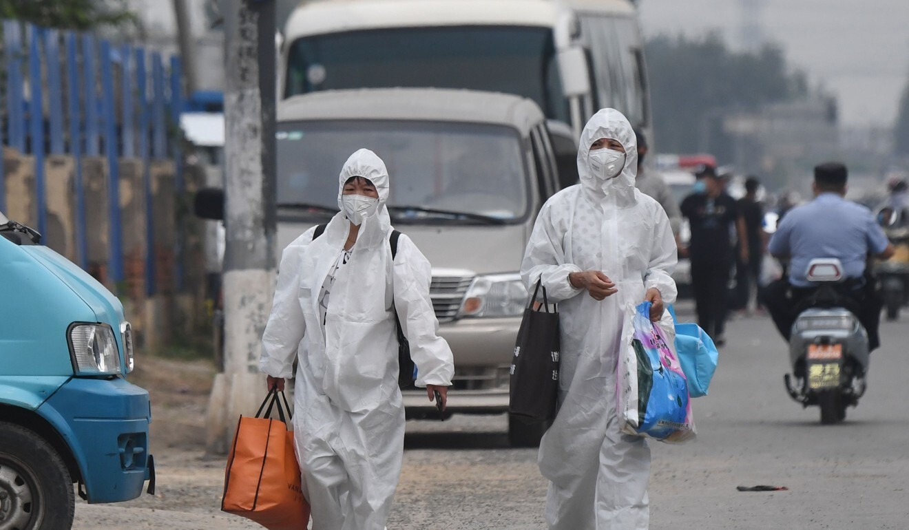 Two women wear protective suits as they walk on a street near the closed Xinfadi market in Beijing on Saturday. Photo: AFP