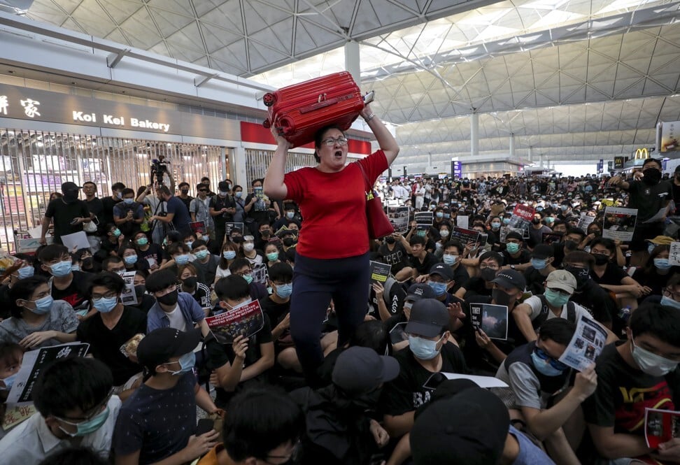 Travellers walk through the anti-government protesters who fill the arrive hall at the Hong Kong International Airport in August last year. Photo: Sam Tsang