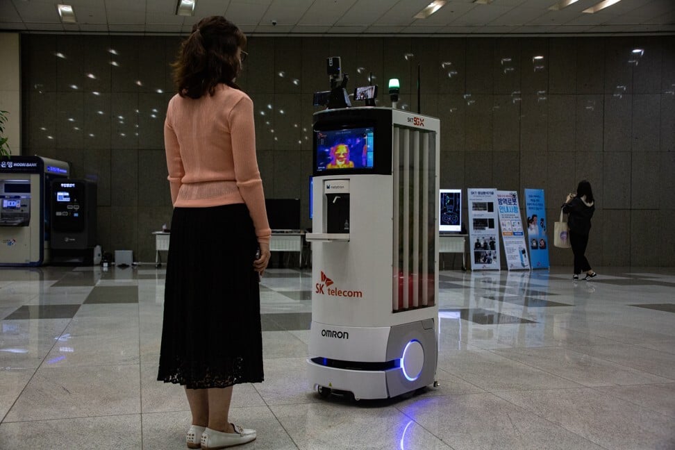 A 5G-powered autonomous robot, centre, from SK Telecom and Omron Electronics Korea Co, used for screening and body temperature checks, is seen during a demonstration event at the mobile network operator’s headquarters in Seoul, South Korea, on May 26. Photo: EPA-EFE