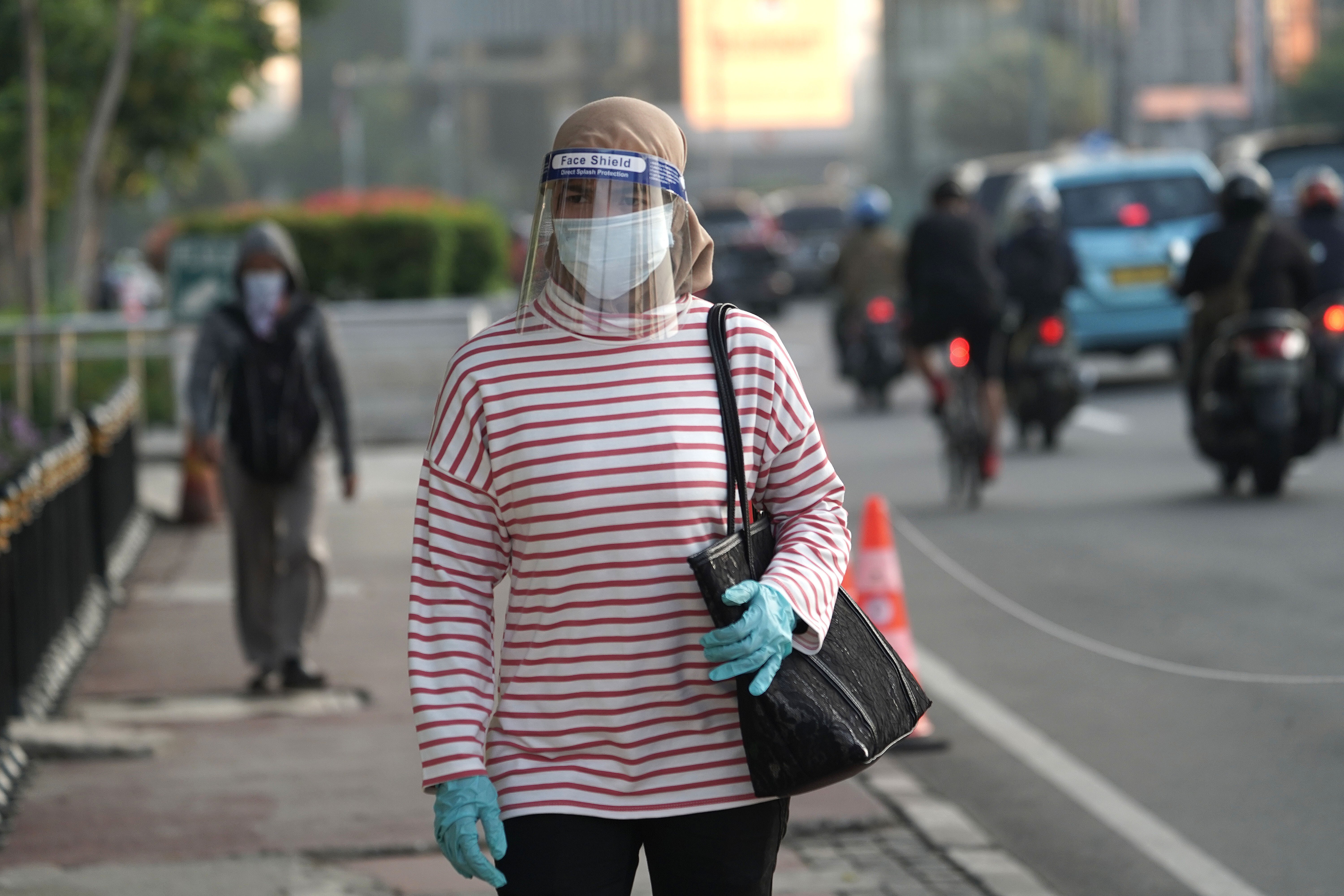 An Indonesian commuter, wearing a protective mask, gloves and face shield, is pictured in Jakarta before returning to work. The country is easing its partial lockdown and reopening the economy, but coronavirus cases are still on the rise. Photo: Bloomberg