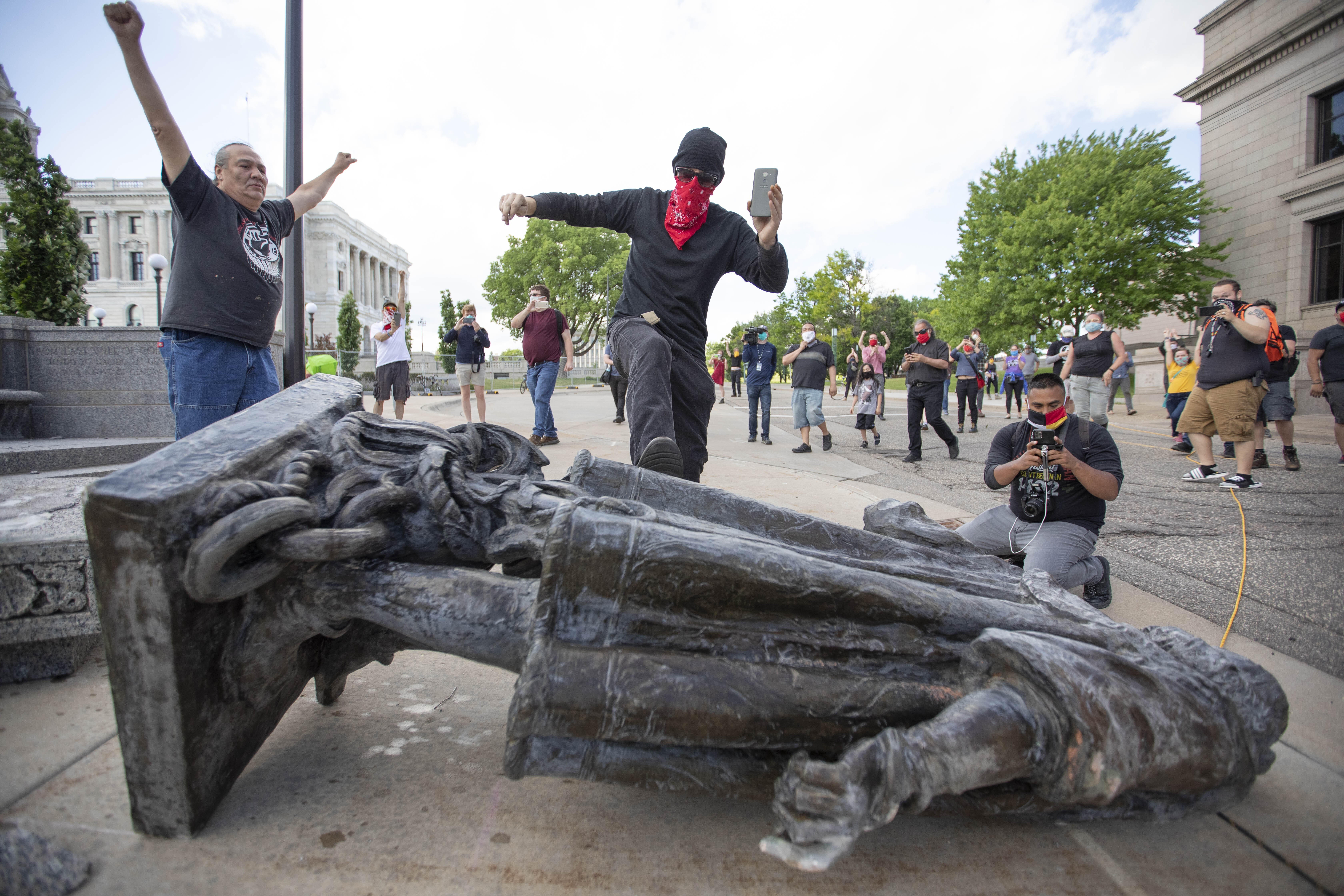 A man kicks a statue of Christopher Columbus after it was pulled down by Native American activists at the State Capitol in Saint Paul, Minnesota, on June 10. Photo: DPA