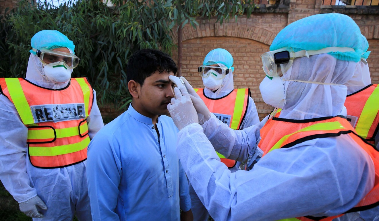 Pakistani rescue workers check the body temperature of a person during a drill in Peshawar. Photo: EPA