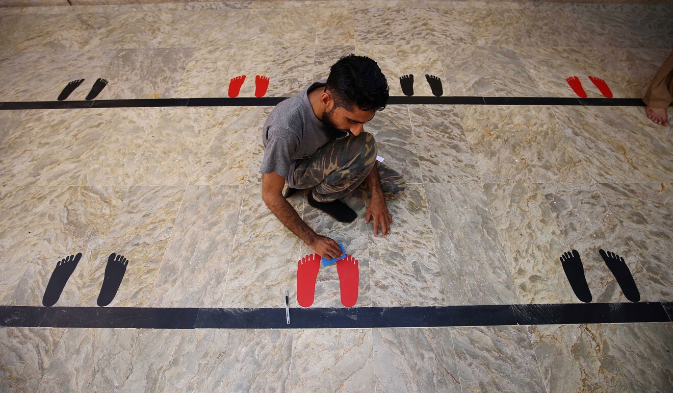 A worker marks the ground for congregants to maintain social distancing during prayers at a mosque in Karachi. Photo: EPA