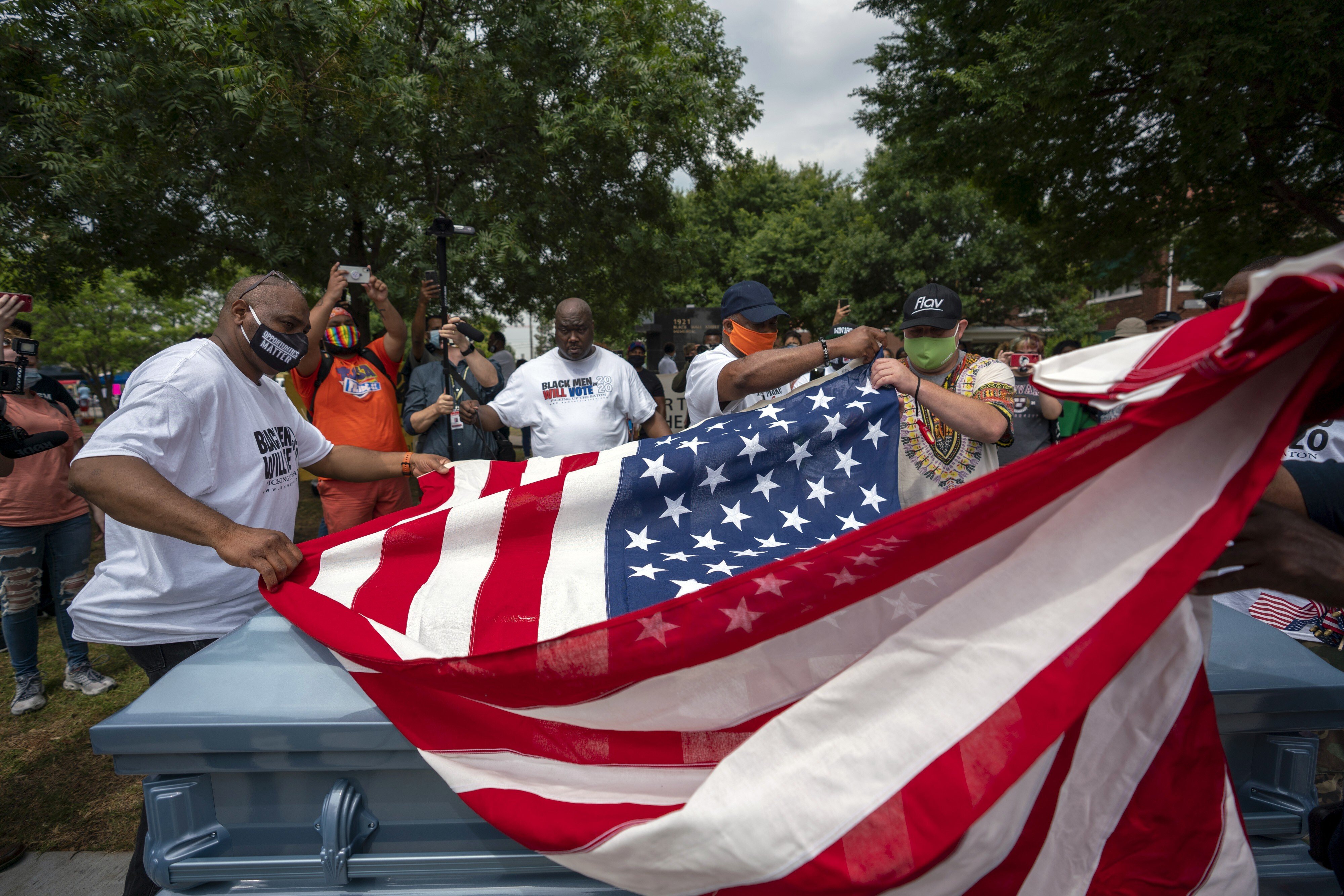 People fold an American flag near an empty casket during a Juneteenth celebration in Tulsa, Oklahoma. Photo: Bloomberg