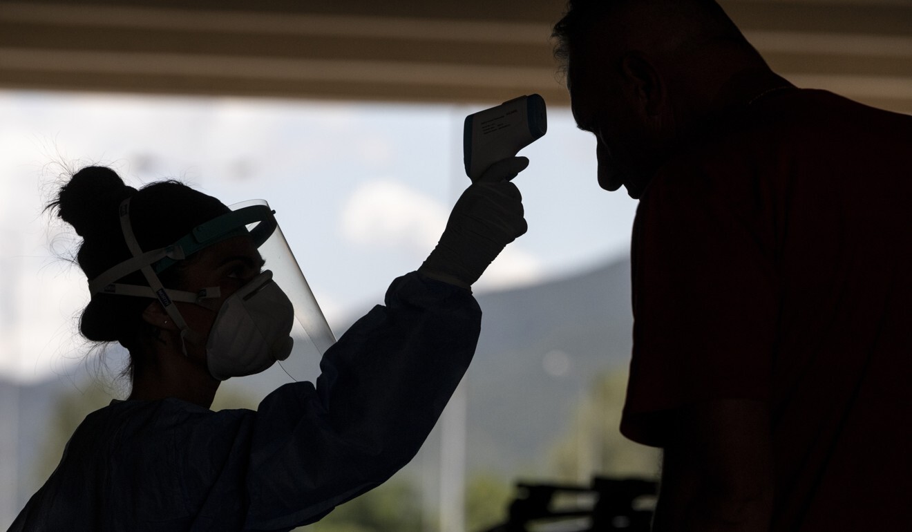 A public health worker takes the temperature of a man during a screening for Covid-19 at the Greek-Bulgarian border. Photo: Bloomberg
