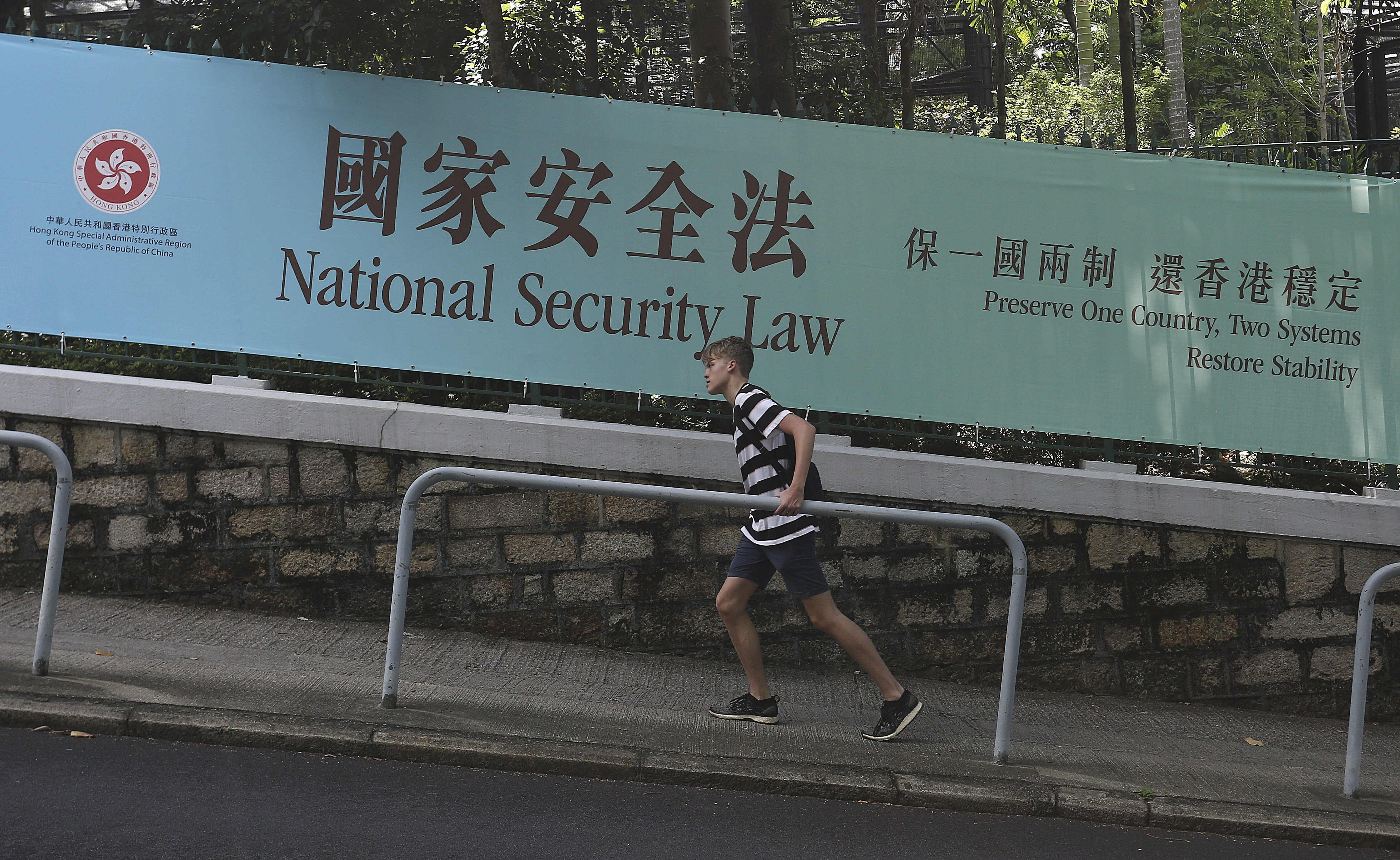 A man walks up a road where a banner promoting the national security law is displayed in Central, Hong Kong, on June 20. Photo: Jonathan Wong