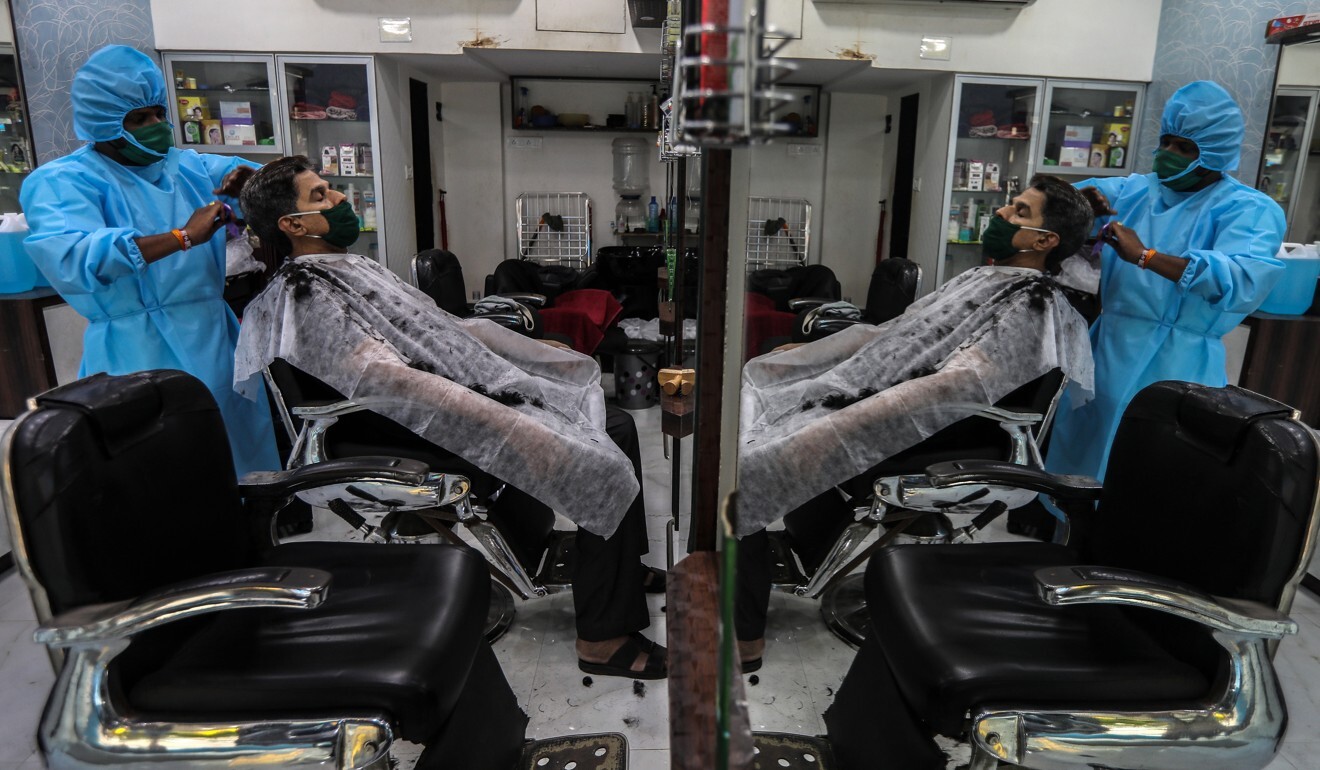 A barber wearing protective gear gives a customer a haircut at a salon in Mumbai. Photo: EPA