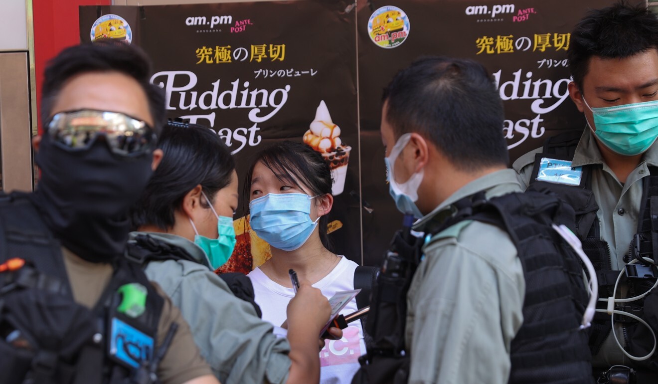 Officers conduct a search on a woman amid a small protest. Photo: EPA-EFE