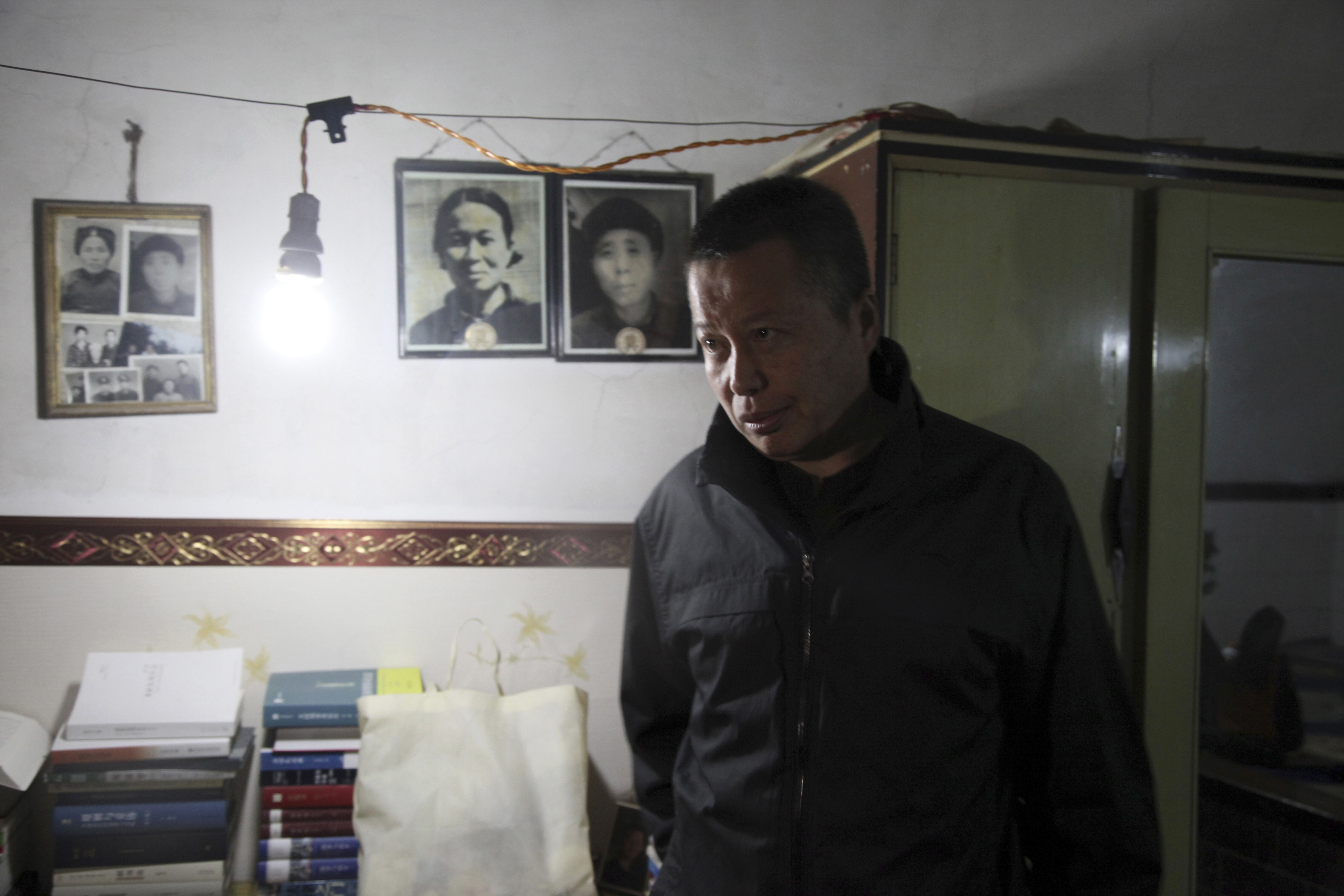 In this 2015 file photo, Gao Zhisheng walks past photos of his relatives in a cave home where he is confined in Shaanxi province. He tried to escape in August 2017 but was captured and his whereabouts are unknown. Photo: AP