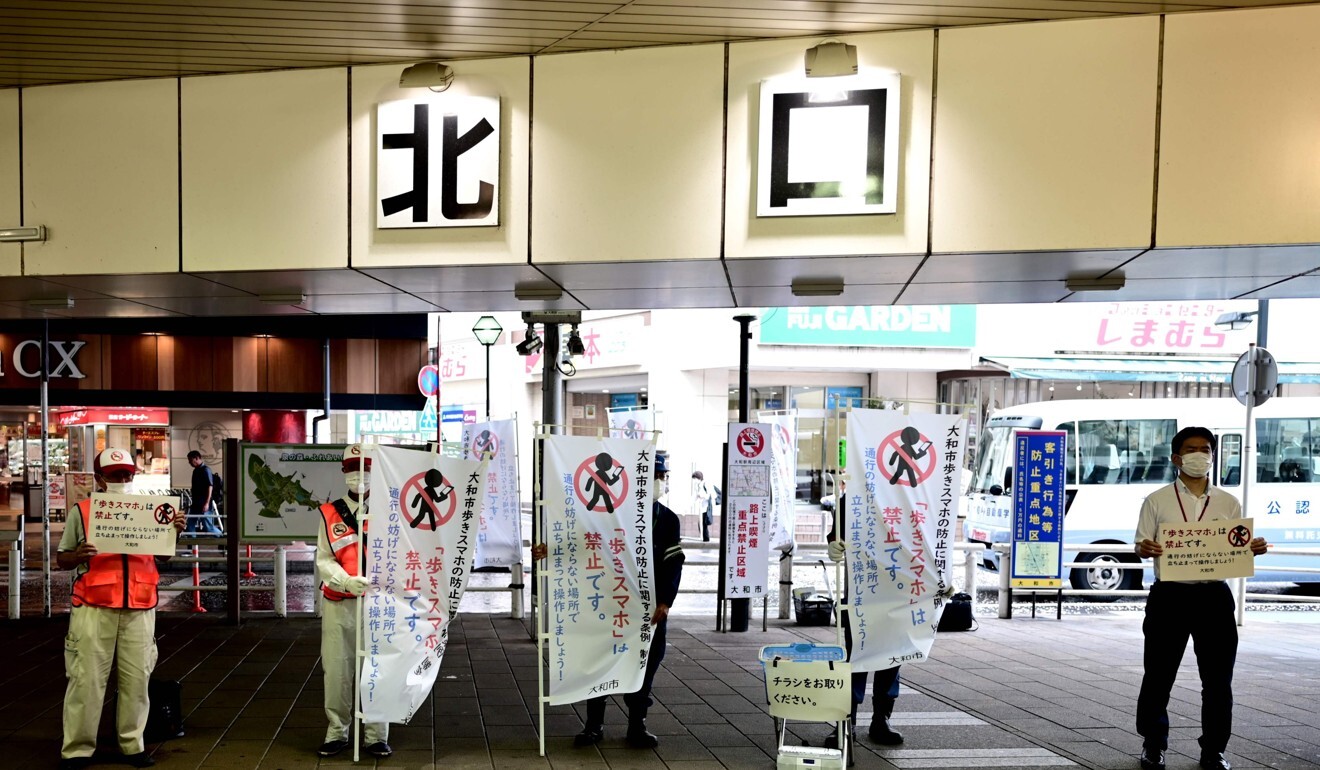 Officials hold banners at a train station in Yamato. Photo: AFP