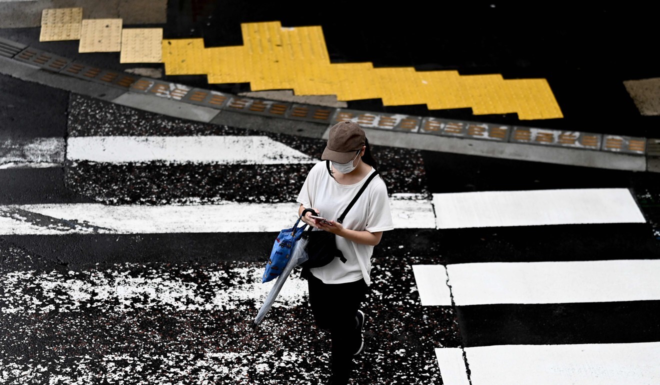 A woman uses her phone while crossing a street in Yamato. Photo: AFP