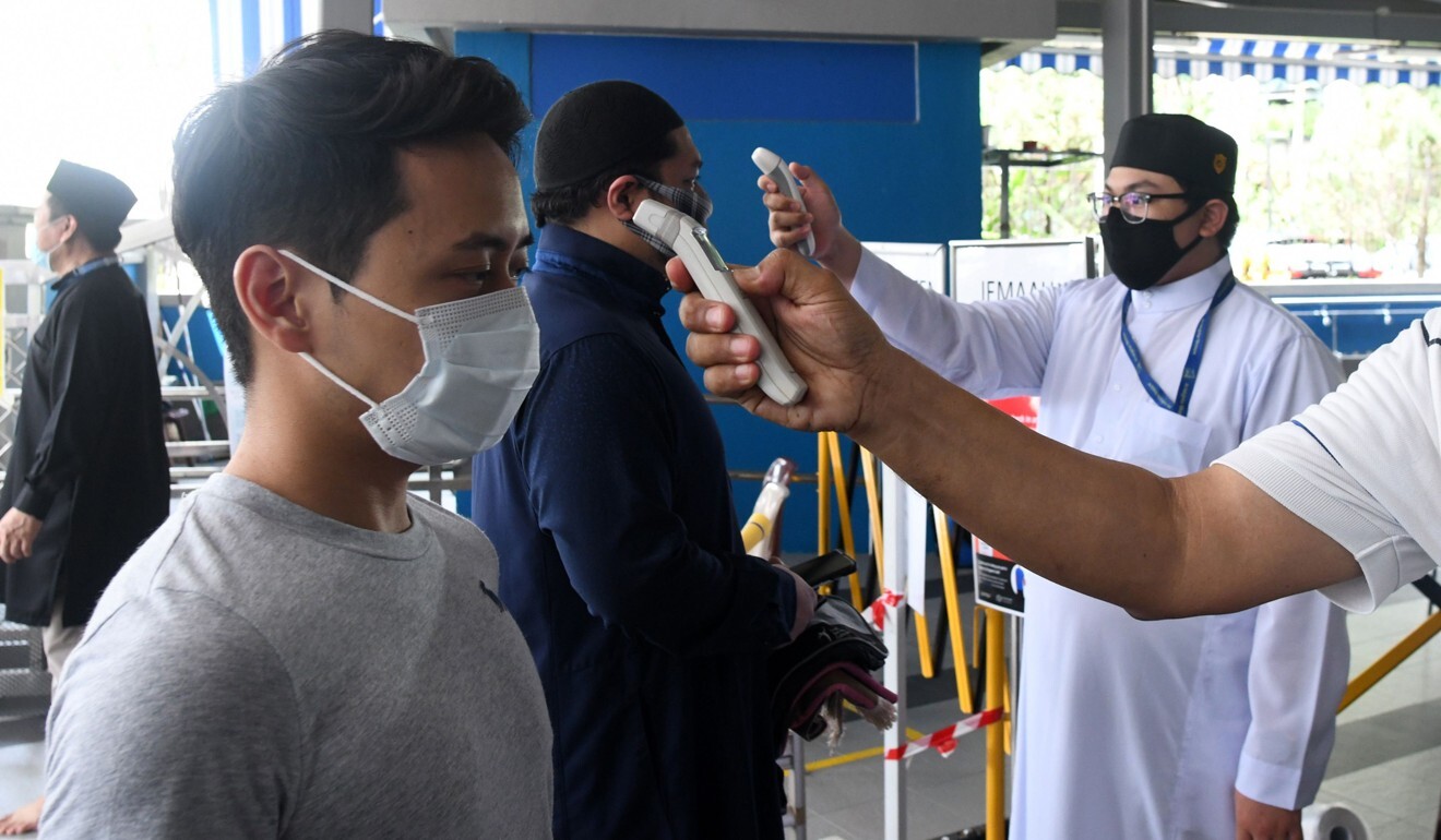 A mosque official checks Muslim devotees’ temperature before Friday prayers. Photo: AFP