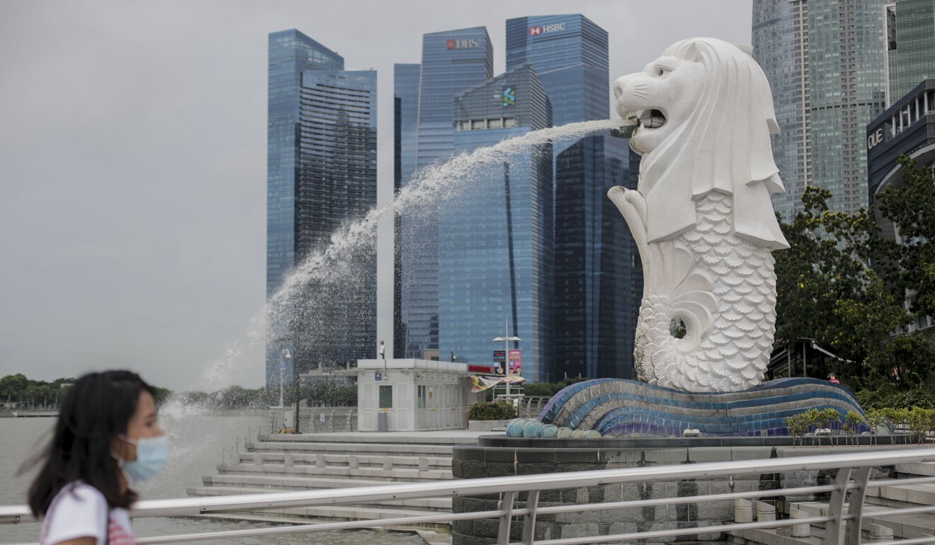 A woman wearing a mask walks past the Merlion Statue in Singapore. Photo: EPA