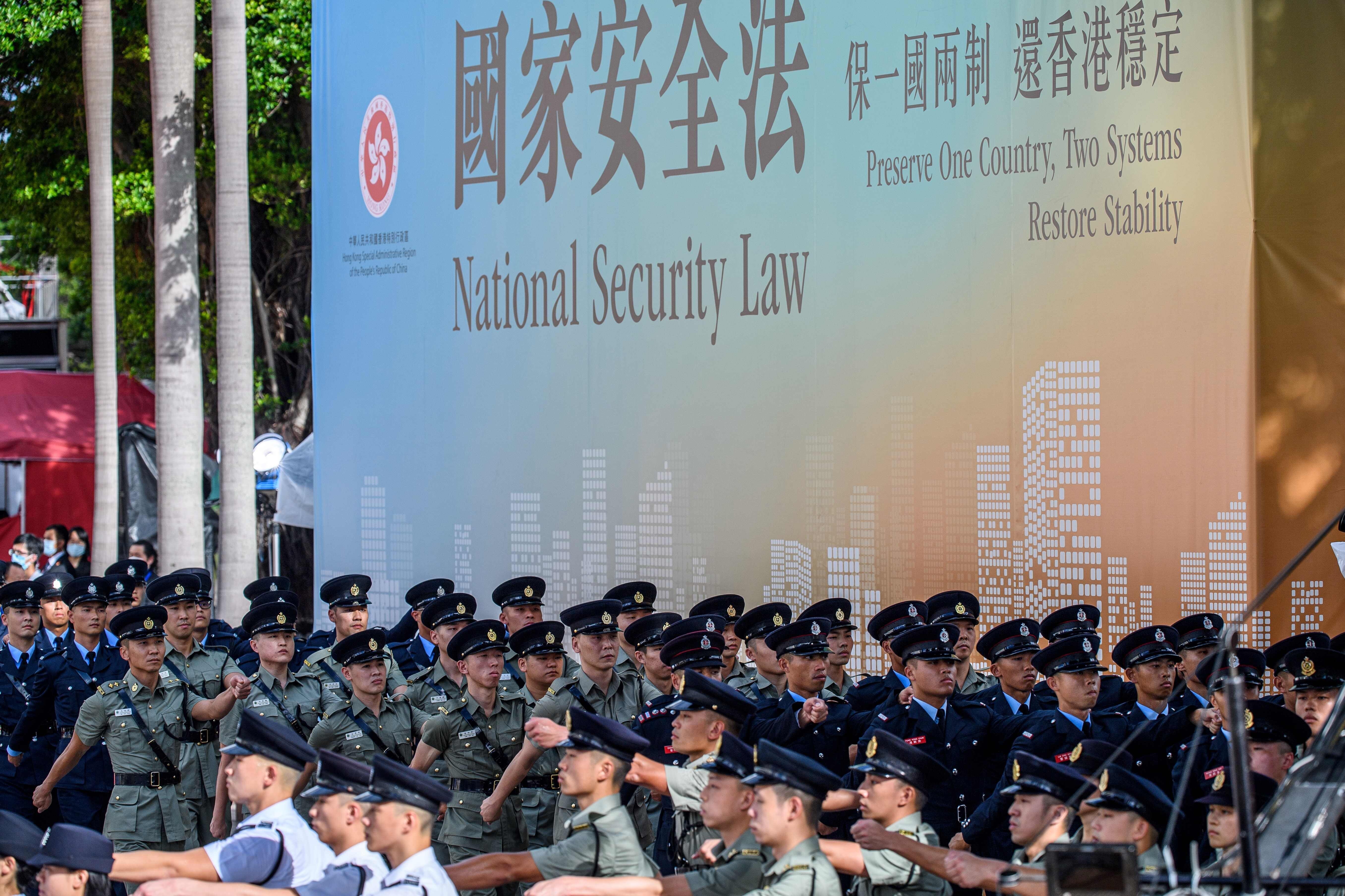 Disciplined forces march next to a banner supporting the new national security law, at the end of a flag-raising ceremony to mark the 23rd anniversary of Hong Kong’s handover in Wan Chai on July 1. Photo: AFP