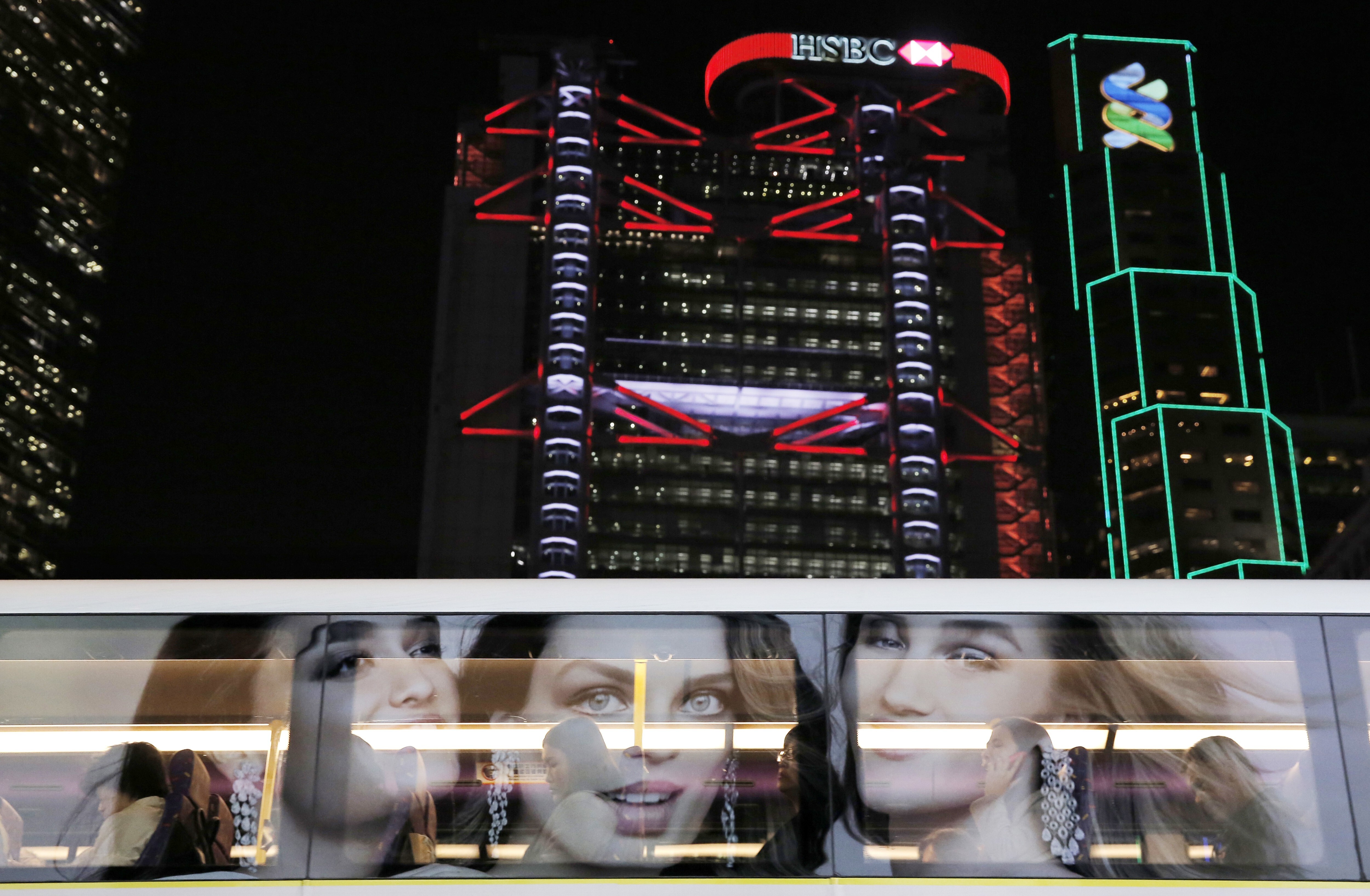An advert is reflected on a bus window, with the Hong Kong headquarters of HSBC and Standard Chartered in the background. Photo: AP