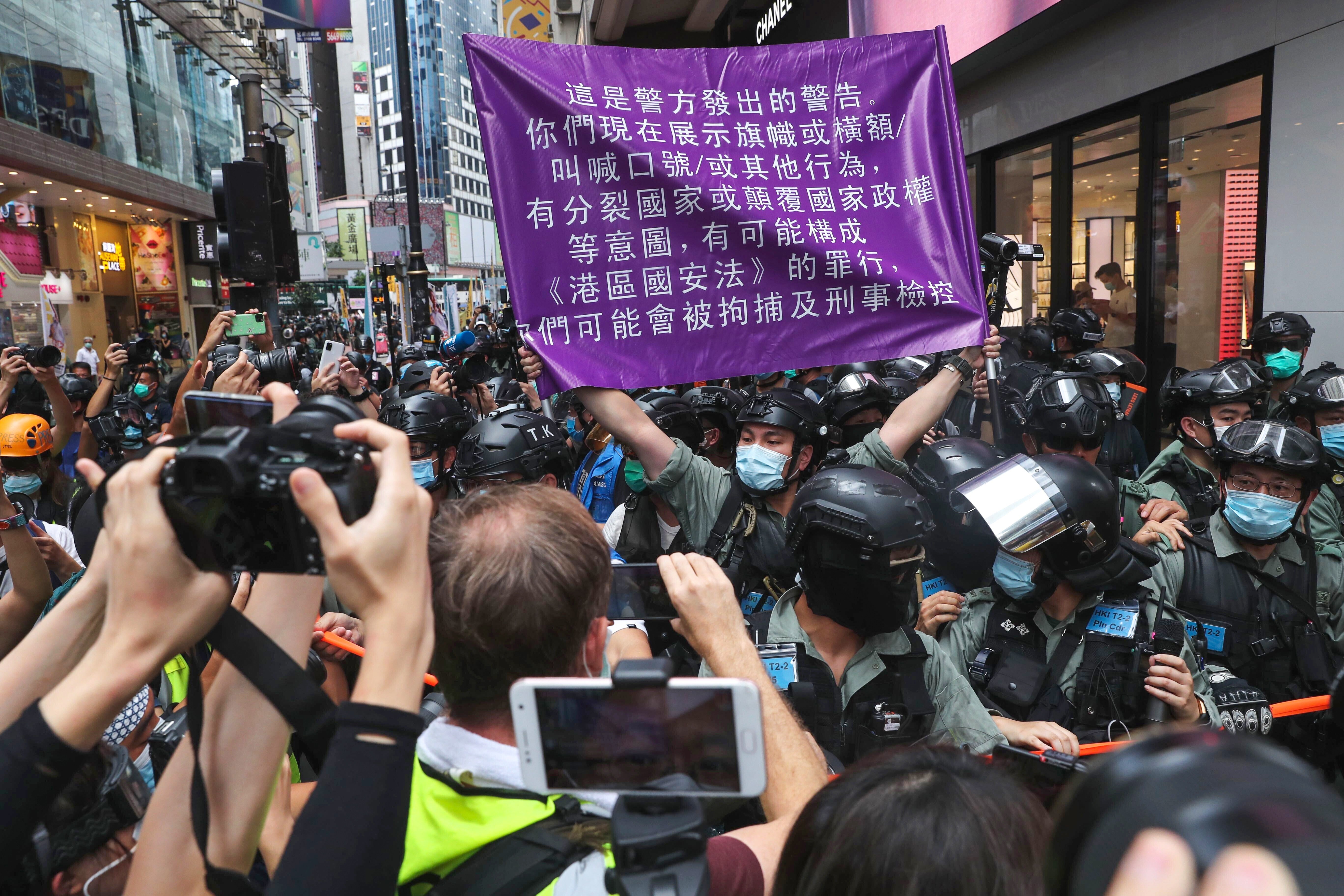 A police officer in riot gear holds up a purple flag warning anti-government protesters they may be violating the national security law during an illegal demonstration in Causeway Bay on July 1, the 23rd anniversary of the establishment of the Hong Kong Special Administrative Region. Photo: Sam Tsang