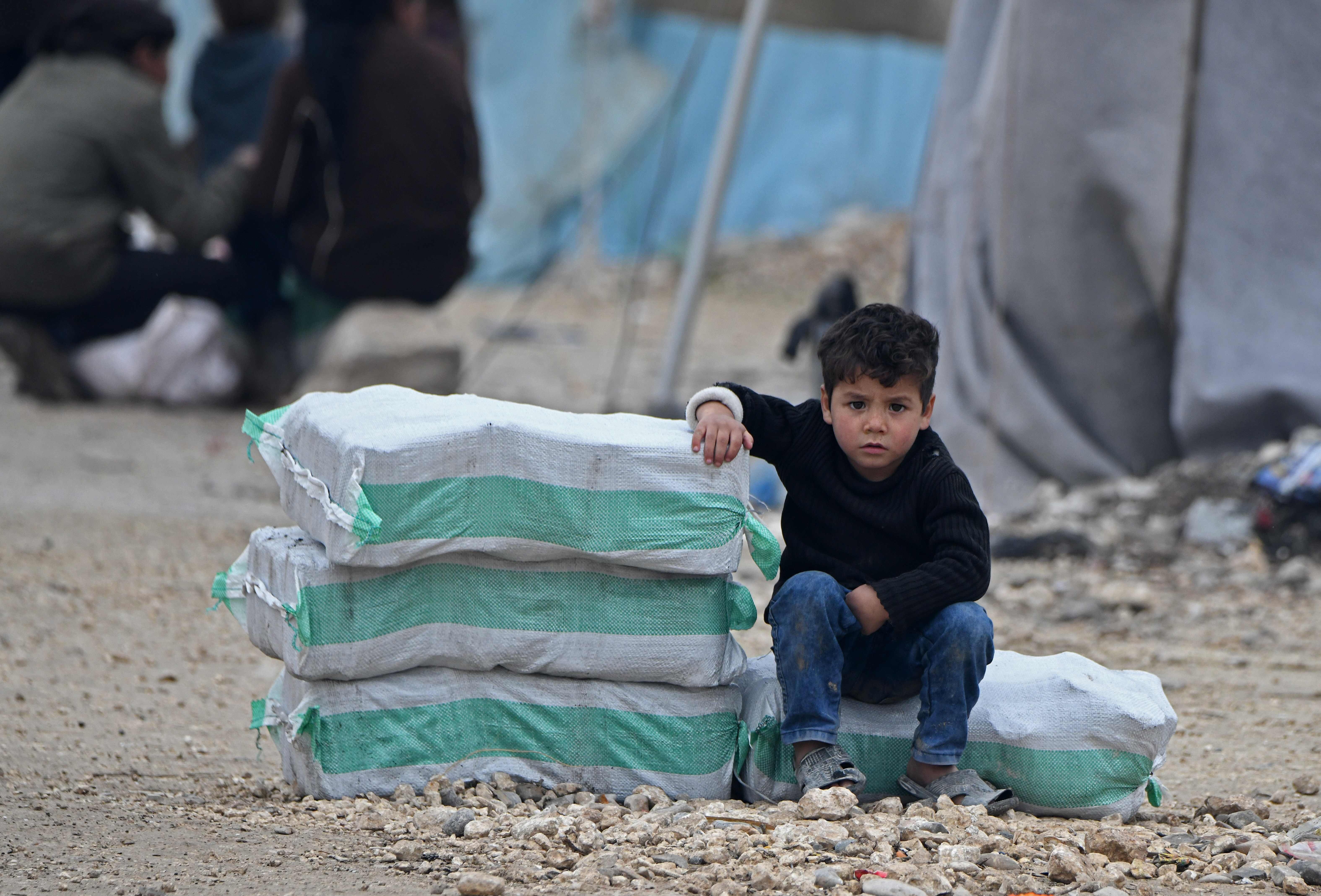 A Syrian boy sits next to humanitarian aid in a camp on February 21. A UN Security Council resolution for a global ceasefire to allow coronavirus aid to the most vulnerable is mired in disagreement. Photo: AFP