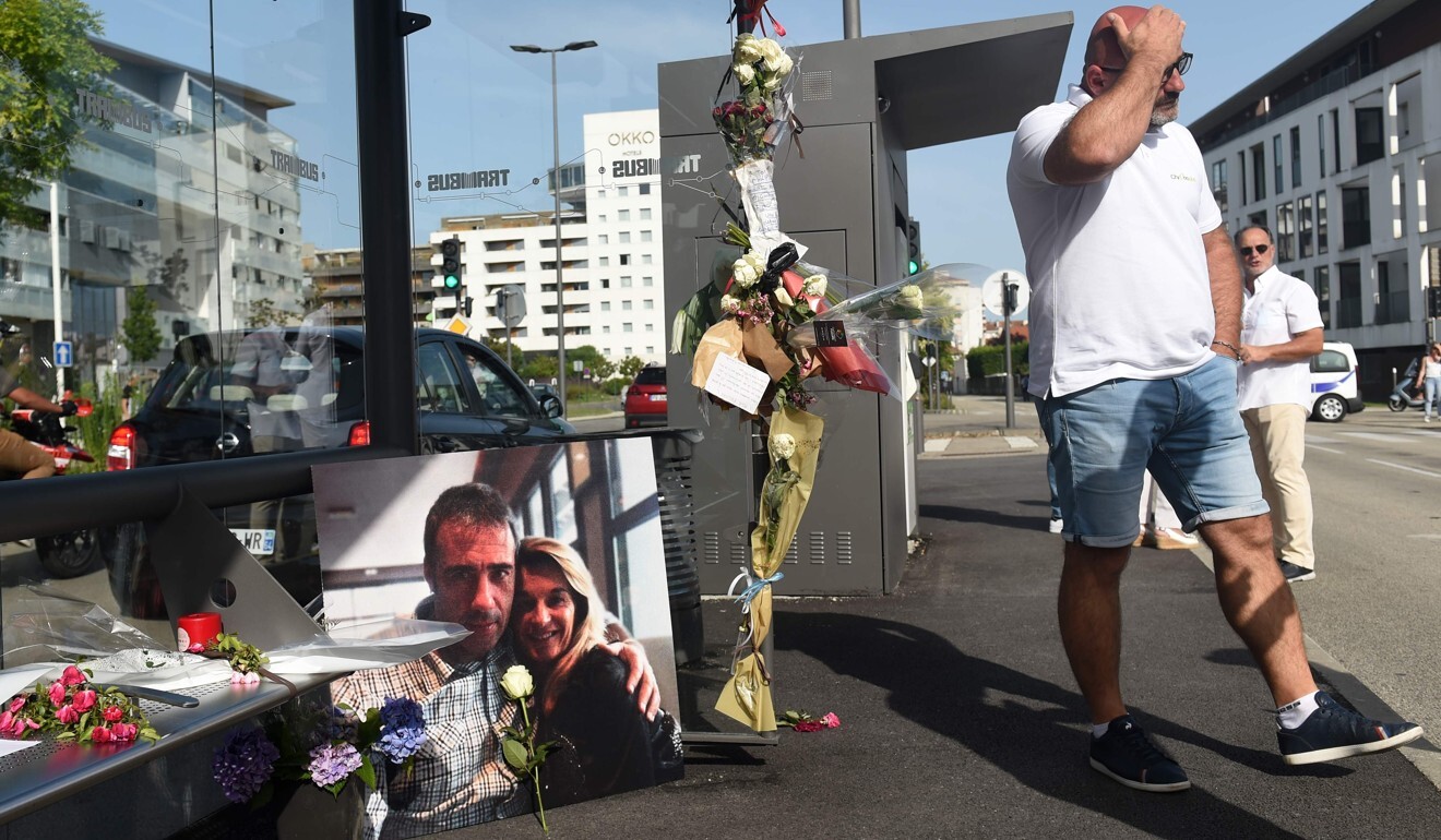 A man walks past a memorial featuring a picture of Philippe Monguillot and his wife. Photo: AFP