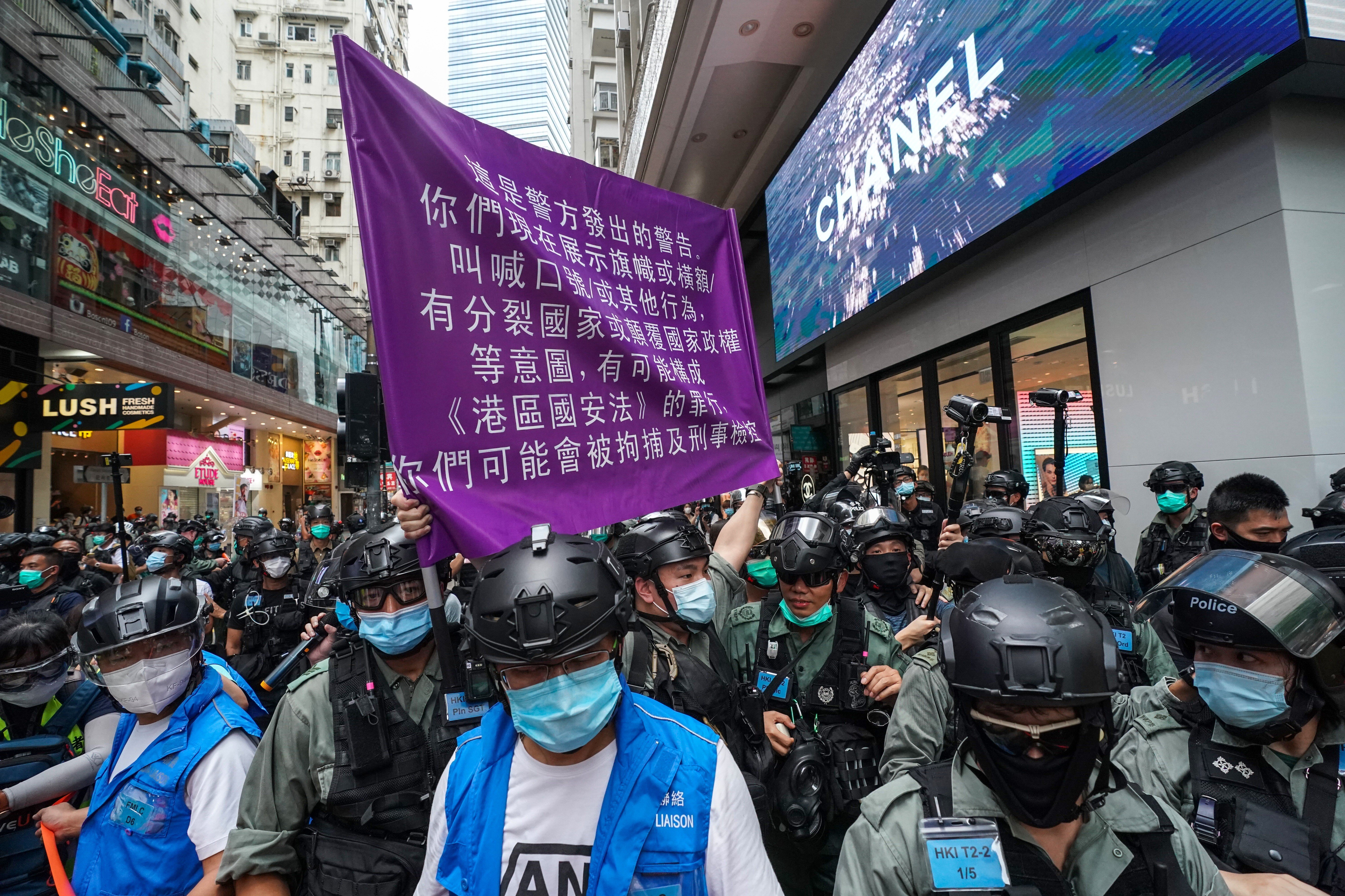 A Hong Kong police officer holds up a flag warning protesters they are violating the national security law, during a demonstration in Causeway Bay on July 1. Photo: Felix Wong