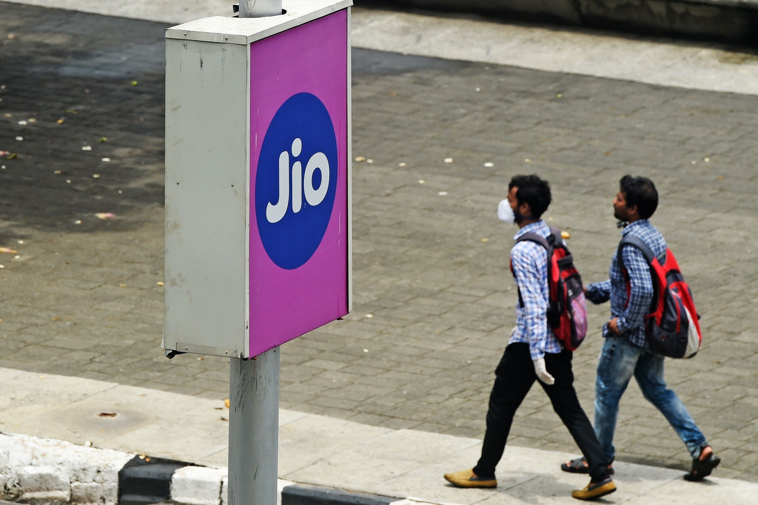 Commuters walk past a board advertising Reliance Jio in Mumbai on June 19, 2020. Photo: AFP