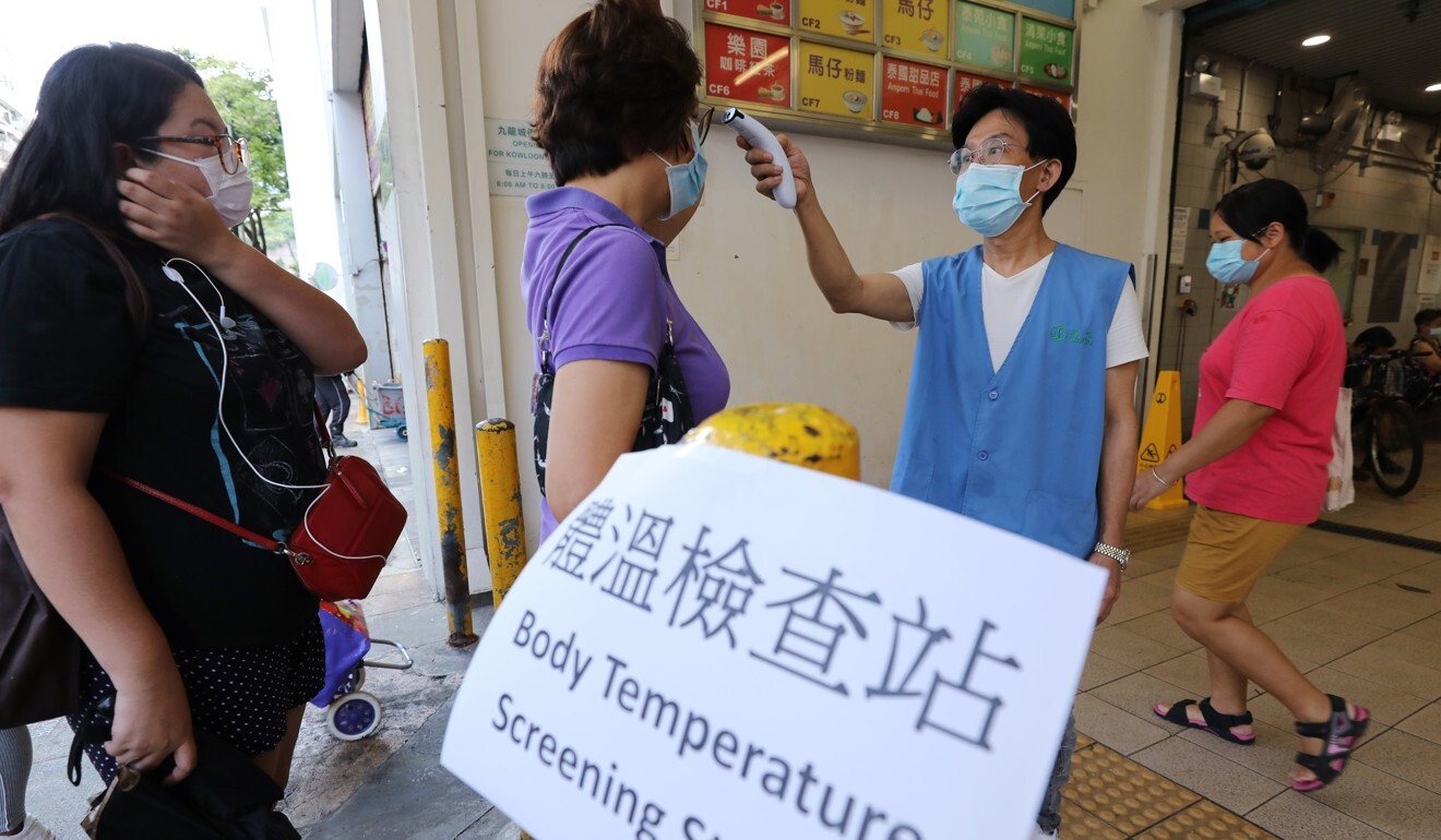 Staff members check the temperature of patrons at a wet market in Kowloon City. Photo: May Tse