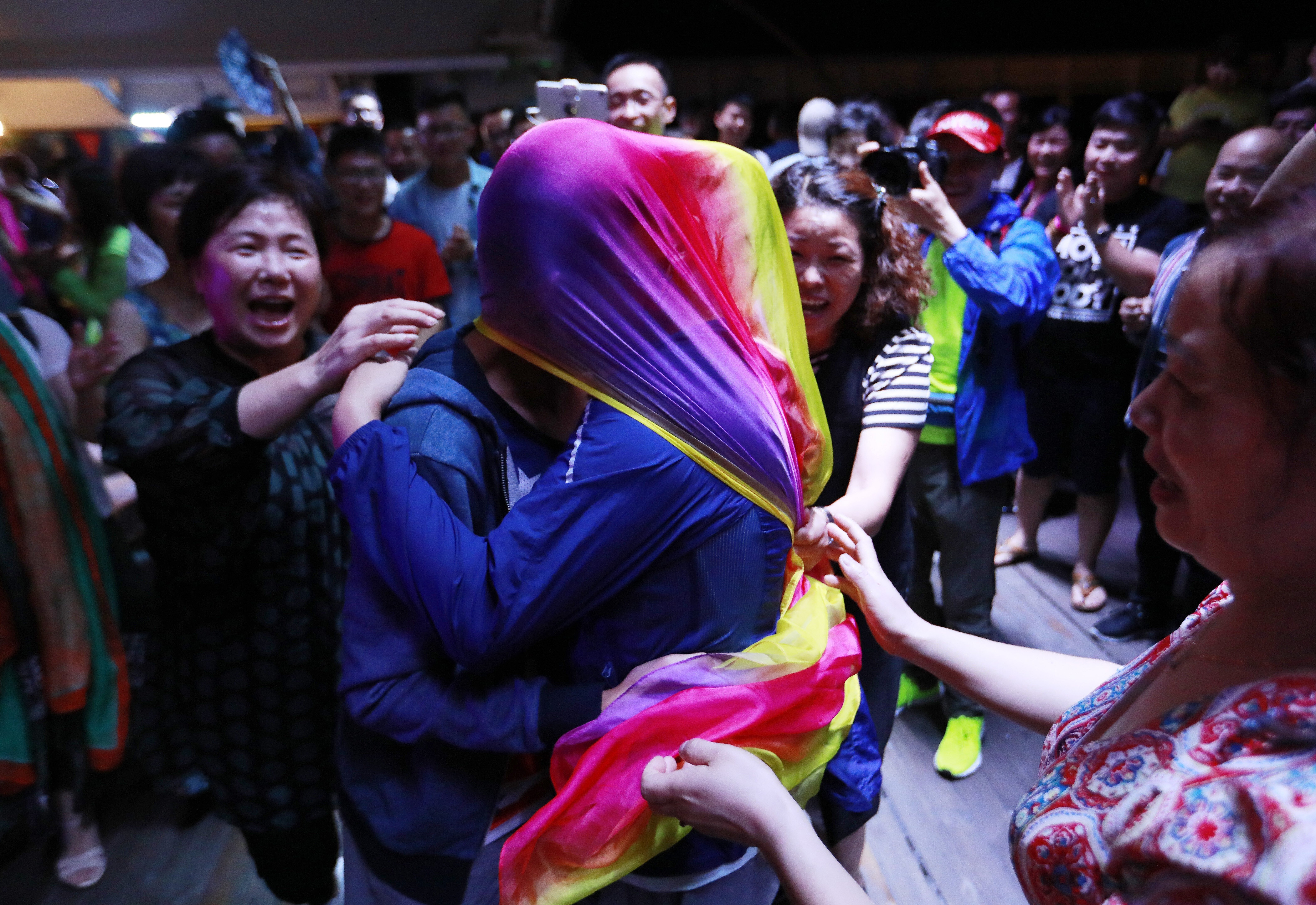 A gay couple kisses under a rainbow-coloured scarf during a party after a mass wedding organised by the Parents and Friends of Lesbians and Gays (PFLAG) China organisation on a cruise in the open seas en route to Sasebo, Japan, on June 15, 2017. About 800 members of the Chinese LGBT community and their parents spent four days on a cruise trip organised by the NGO. Photo: EPA