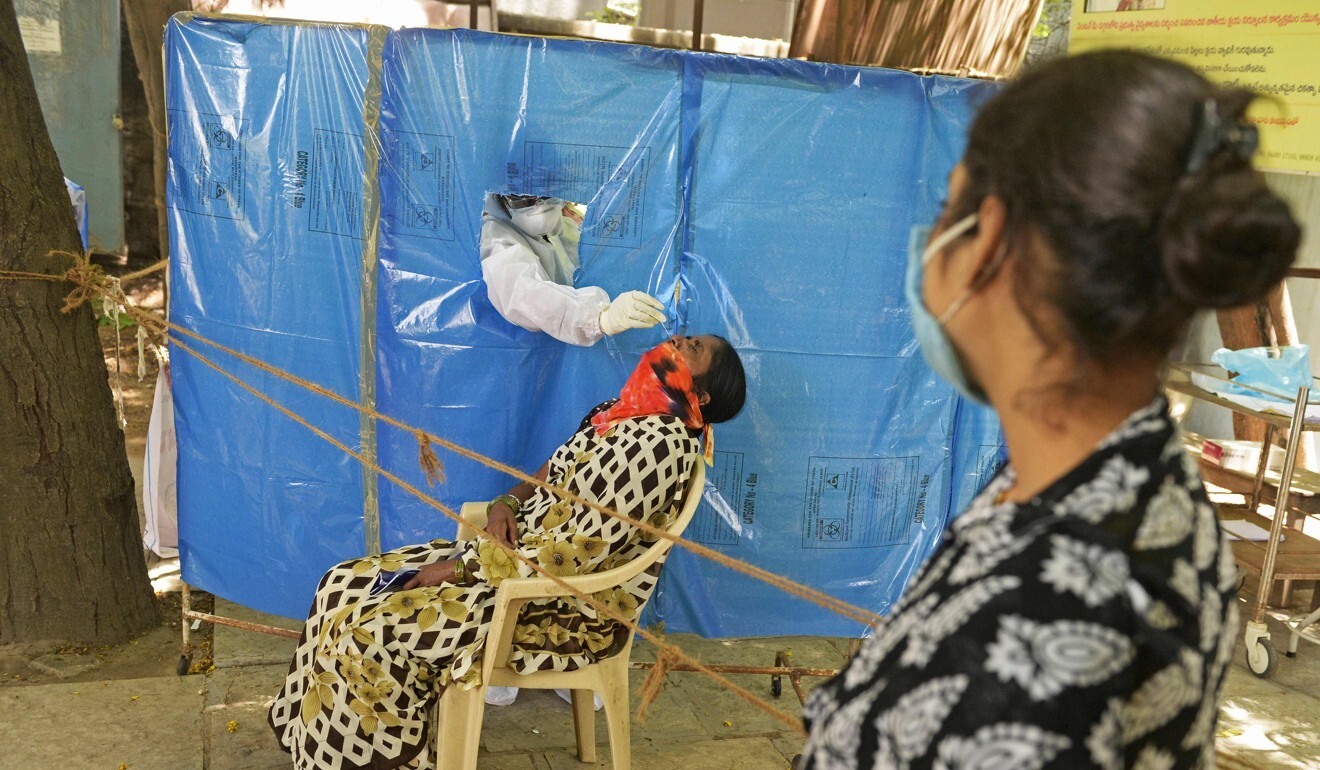 A health worker wearing collects a swab sample at a free testing centre in Hyderabad, India. Photo: AFP