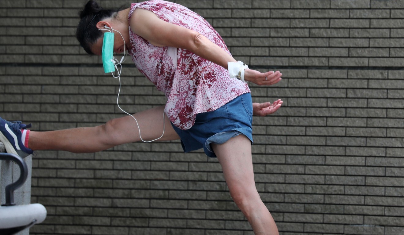 A woman stretches her leg as her face mask hangs on her ear at Quarry Bay. Photo: Xiaomei Chen