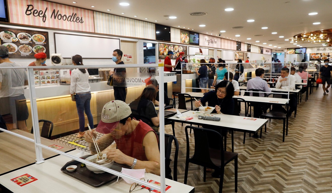 Tables at a food court in Singapore are divided by Plexiglas to guard against transmission of Covid-19. Photo: Reuters