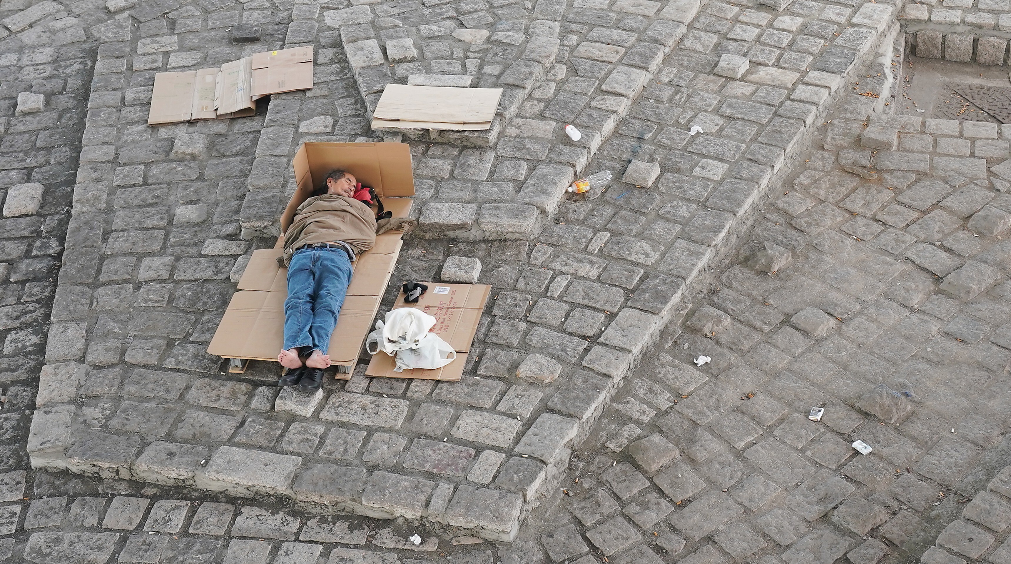 A homeless man sleeps on the ground in Sheung Wan, Hong Kong, on July 25. Photo: Felix Wong