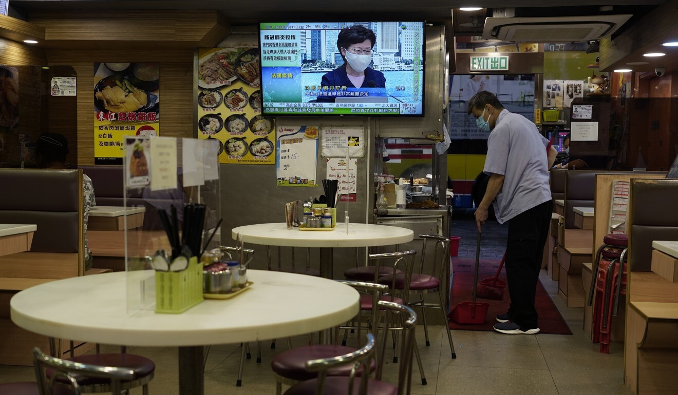 A restaurant employee cleans the floor as a TV screen shows Chief Executive Carrie Lam. Photo: AP