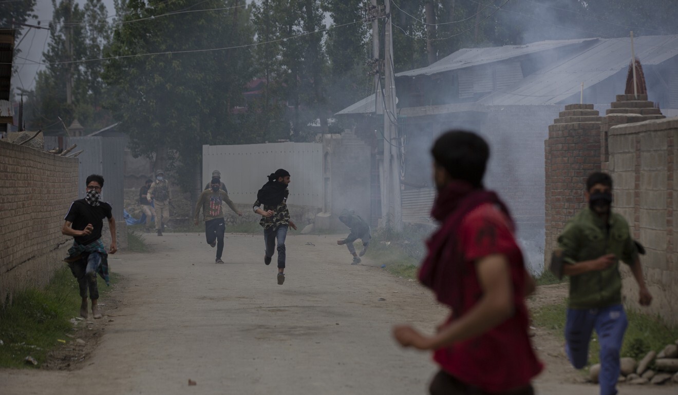 Kashmiri villagers run for cover as policemen fire tear gas at them during a protest against the killing of a civilian in Makhama village, west of Srinagar, on May 13. Photo: AP