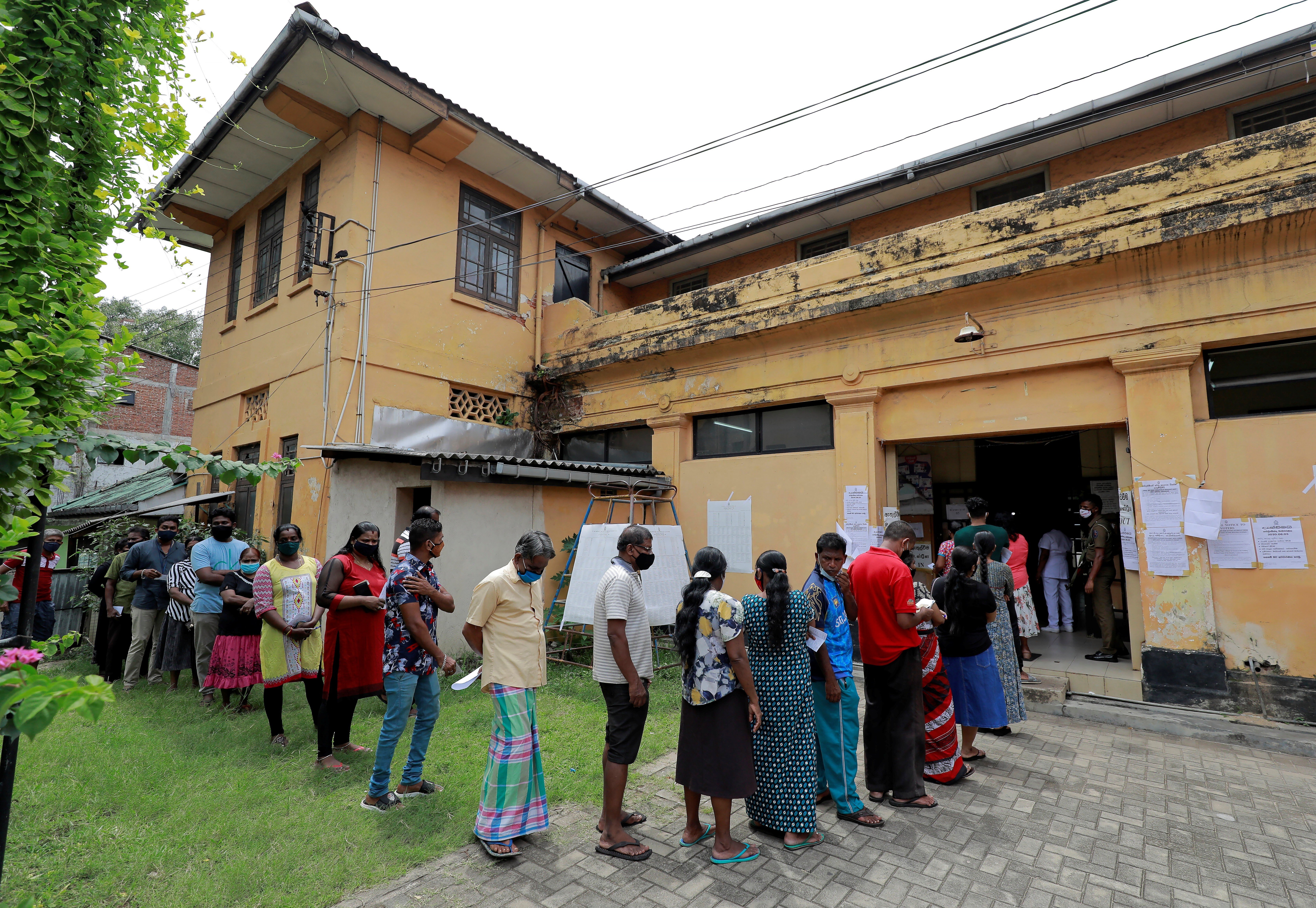 People wearing face masks queue outside a polling station in Colombo to cast their votes in Sri Lanka’s parliamentary election on Friday. Photo: Reuters