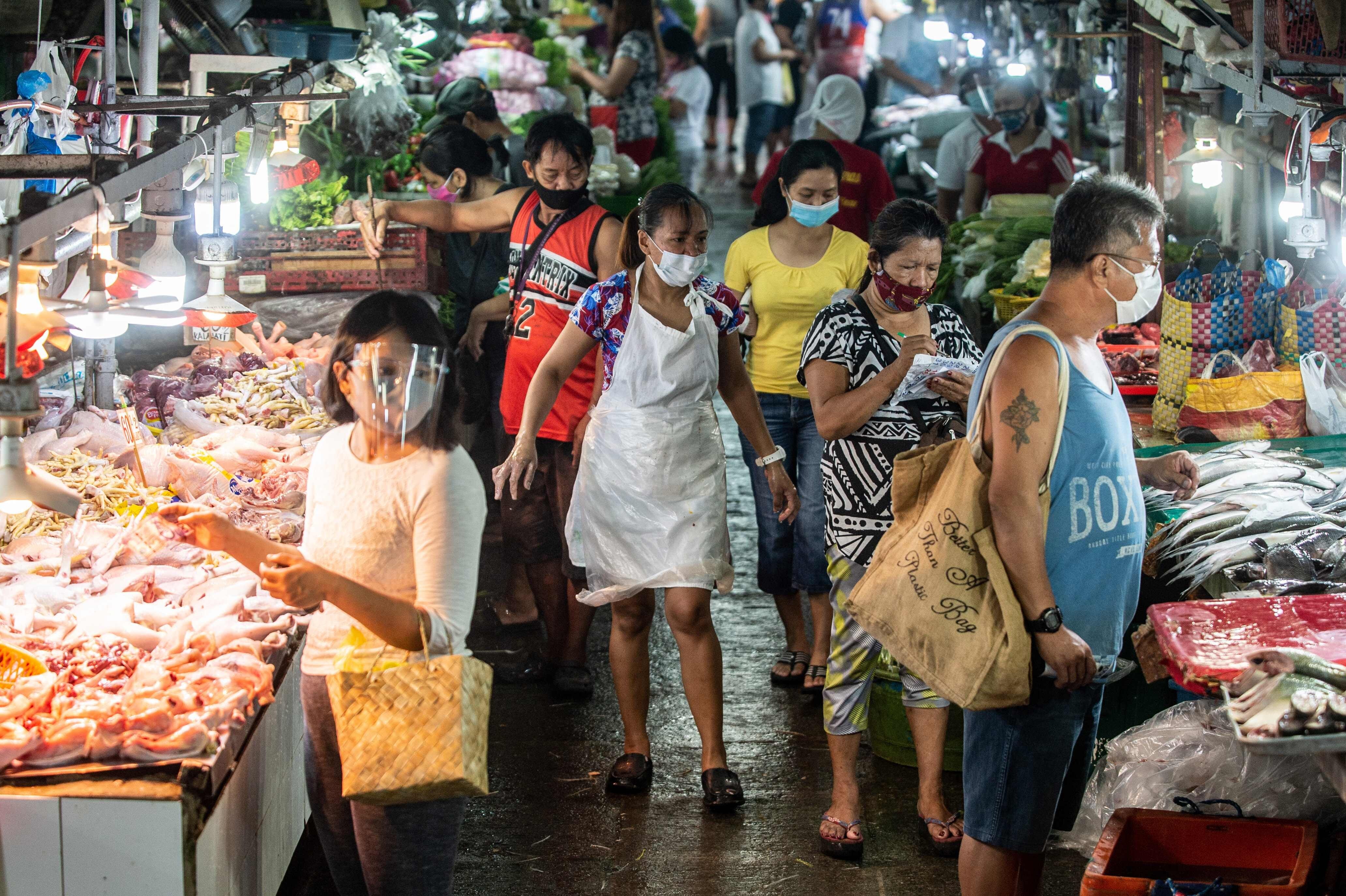 People wearing masks shop for fresh food at a market in Manila. Photo: AFP