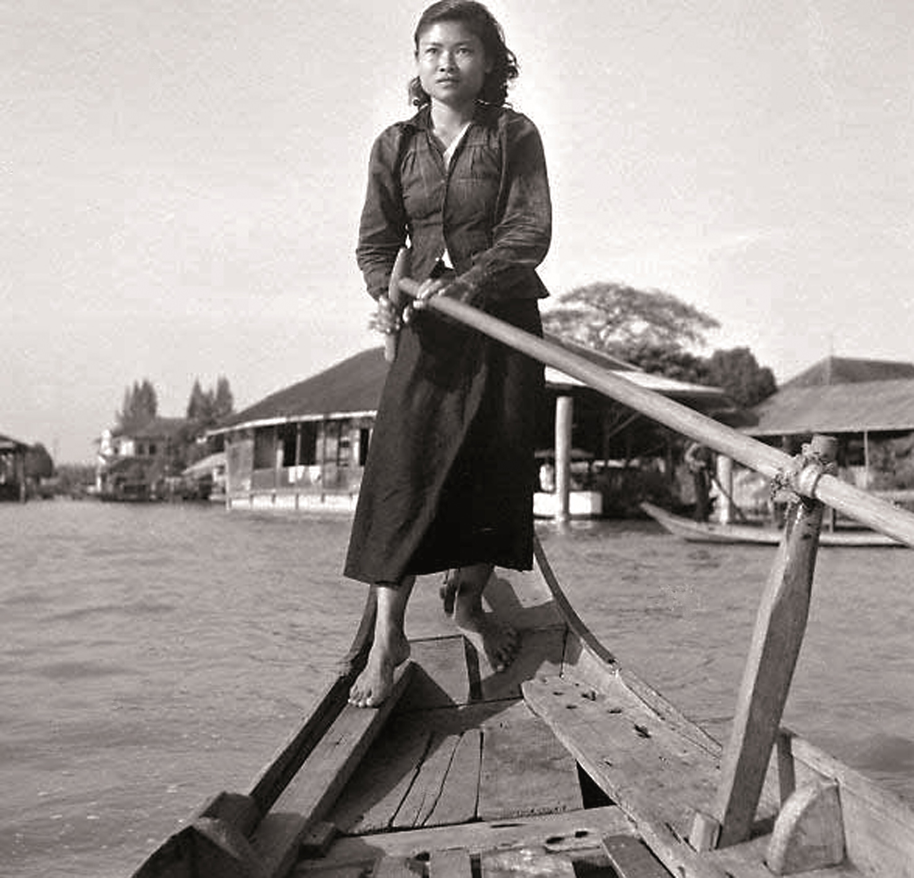 An early Bangkok shot of a Thai woman paddling a sampan on the Chao Phraya River (Note: This is NOT a picture of Khunying Boonpan)/. Photo Credit: Supatra Group.