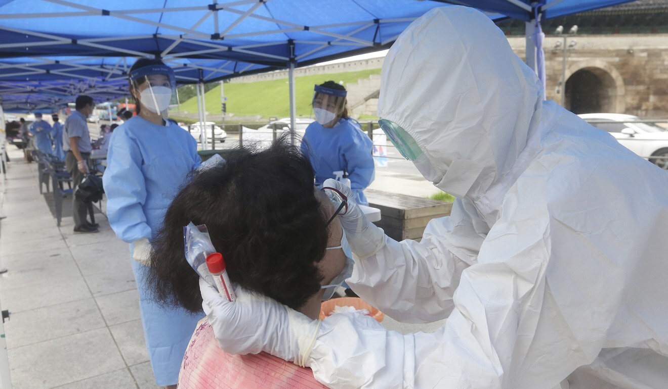 A health worker wearing protective gear takes a swab sample from a woman in Seoul on Monday. Photo: AP