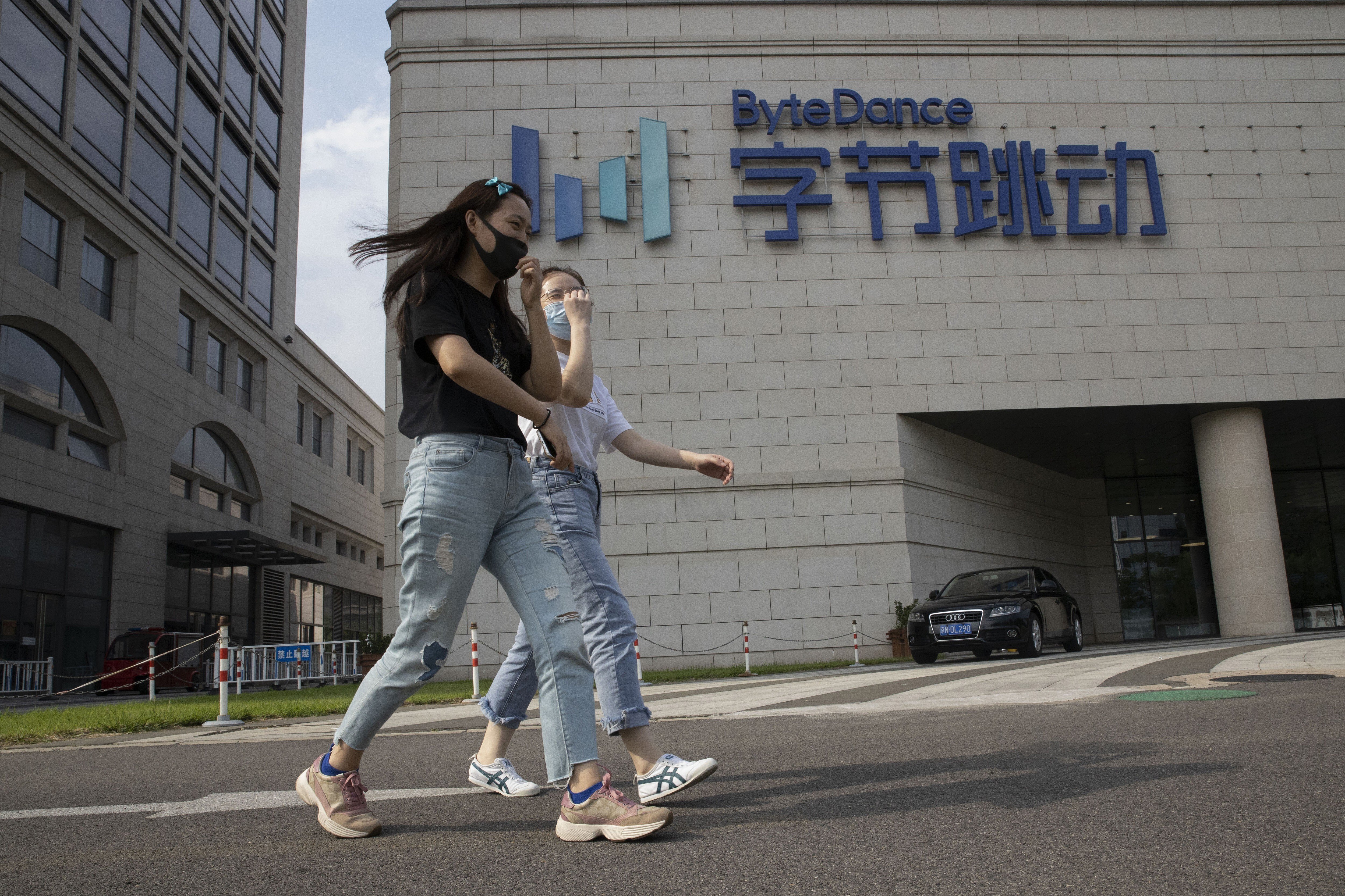 Pedestrians chat as they pass the ByteDance headquarters in Beijing on August 7. US President Donald Trump has ordered a sweeping but unspecified ban on dealings with the Chinese owners of TikTok, and WeChat, although it remains unclear if he has the legal authority to actually ban the apps from the US. Photo: AP