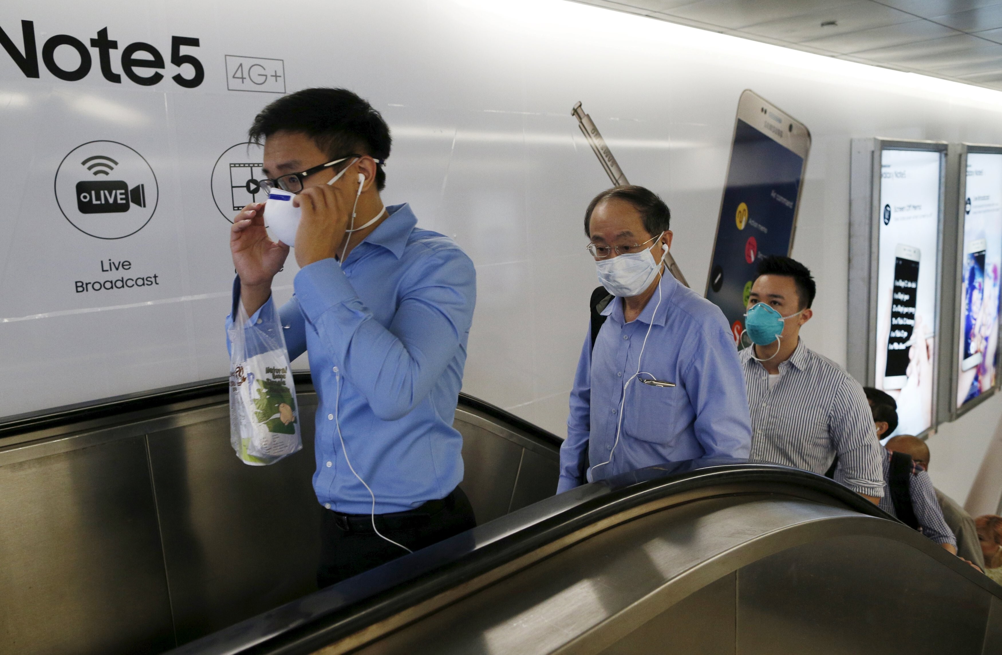 Singaporean officer workers wearing masks leave a train station during the morning commute. Photo: Reuters