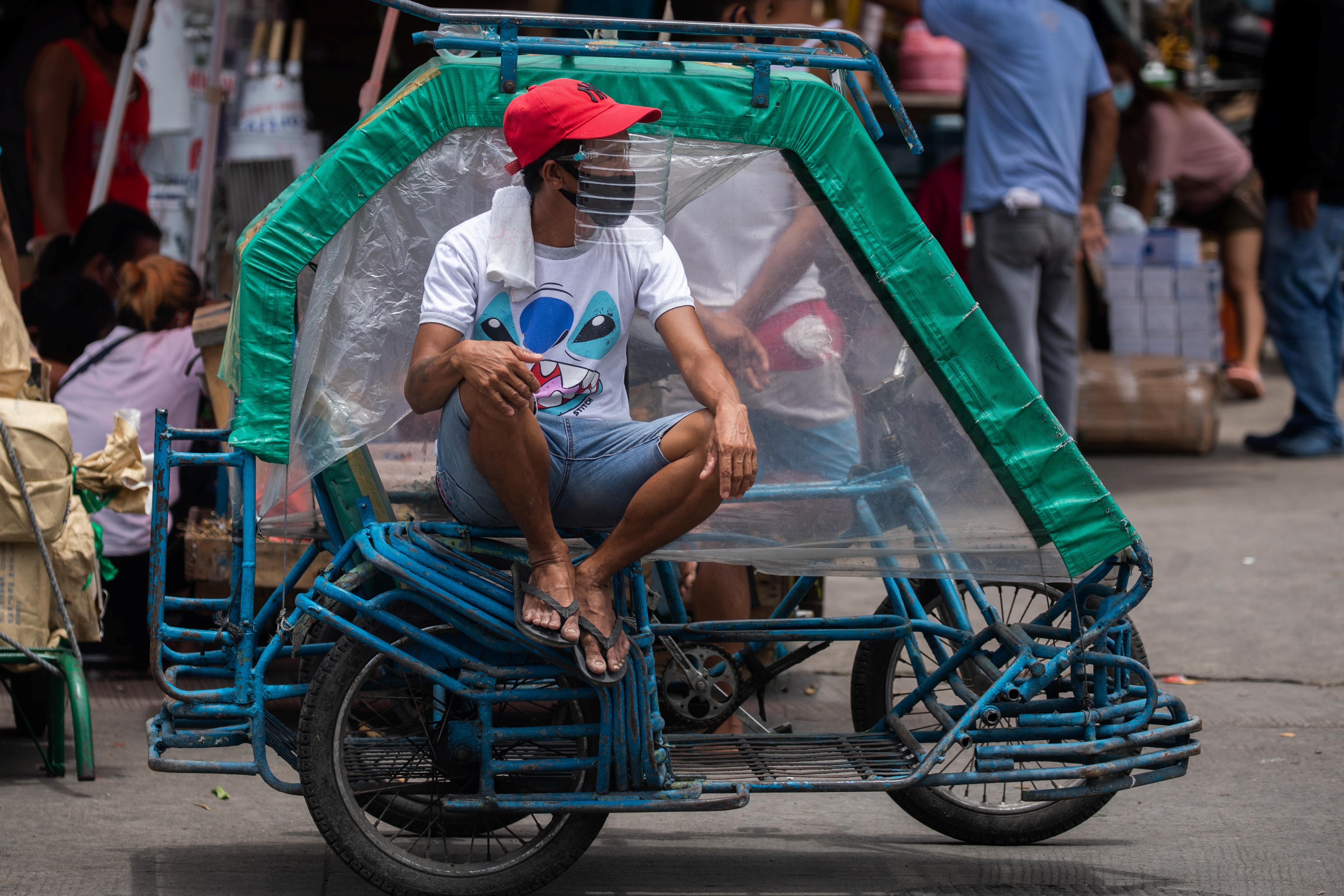 A rickshaw driver wears a face mask and a makeshift face shield made of a water bottle, following their mandatory use in all public transport, amid the coronavirus outbreak in Manila, Philippines. The worst impacts of the pandemic have been felt by informal workers, migrant workers and the poor. Photo: Reuters