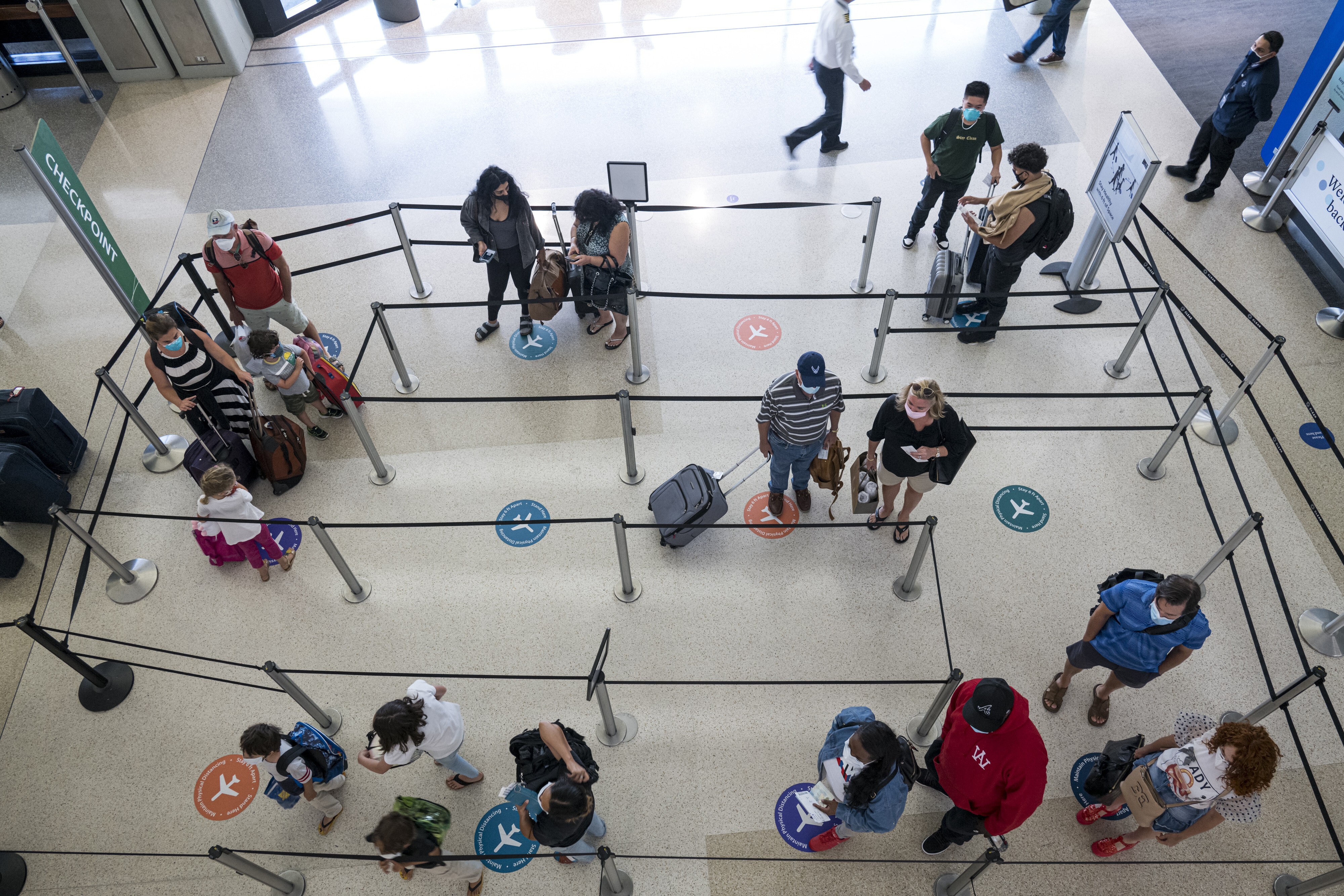 Travellers wearing protective masks stand on social distancing markers while waiting in a security line at the San Francisco International Airport on August 11. Not surprisingly, travel and other sectors facing the greatest impact from the stay-at-home directive were among the worst performers this earnings season. Photo: Bloomberg