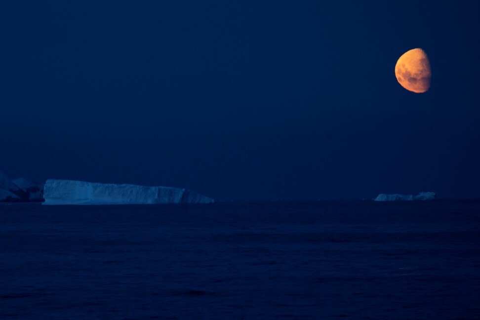 The moon hangs over icebergs near Fournier Bay, Antarctica. Photo: Reuters
