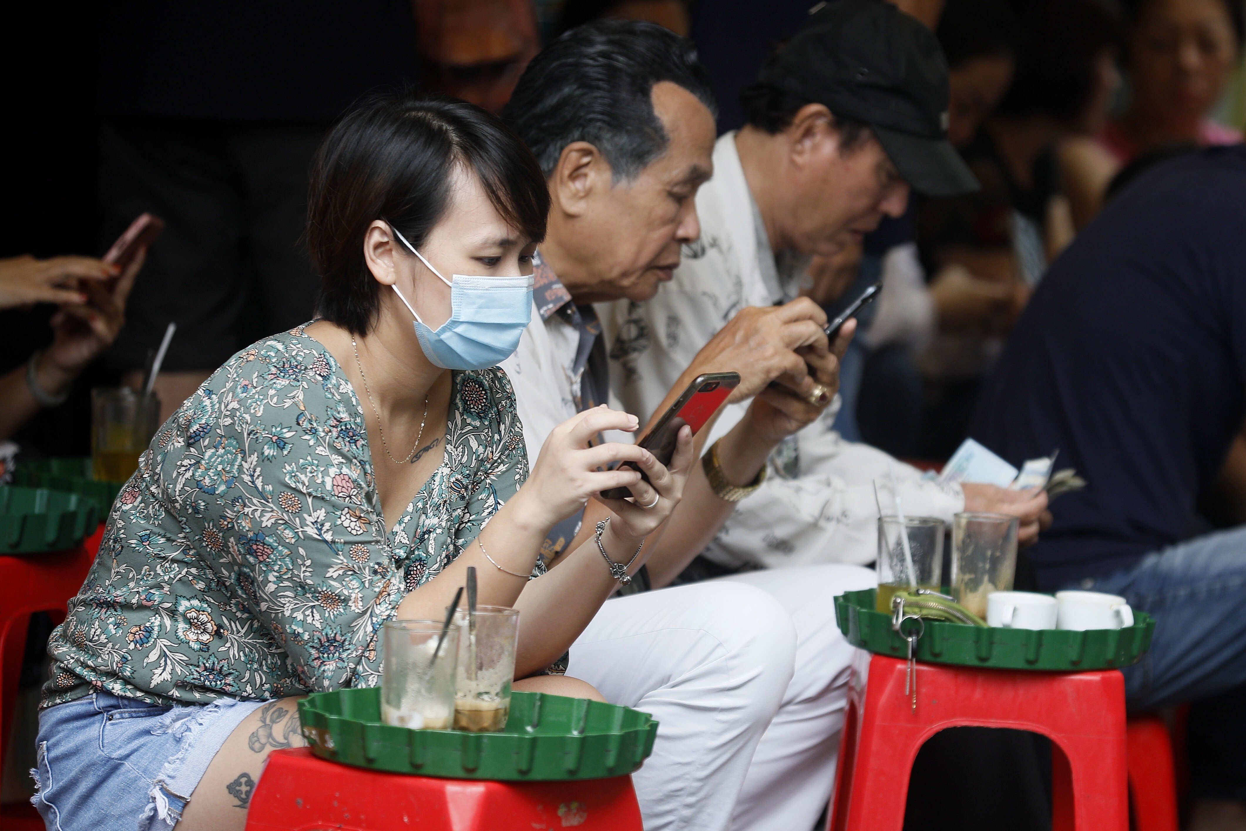 A woman checks her mobile phone at a street cafe in Hanoi. Photo: EPA-EFE