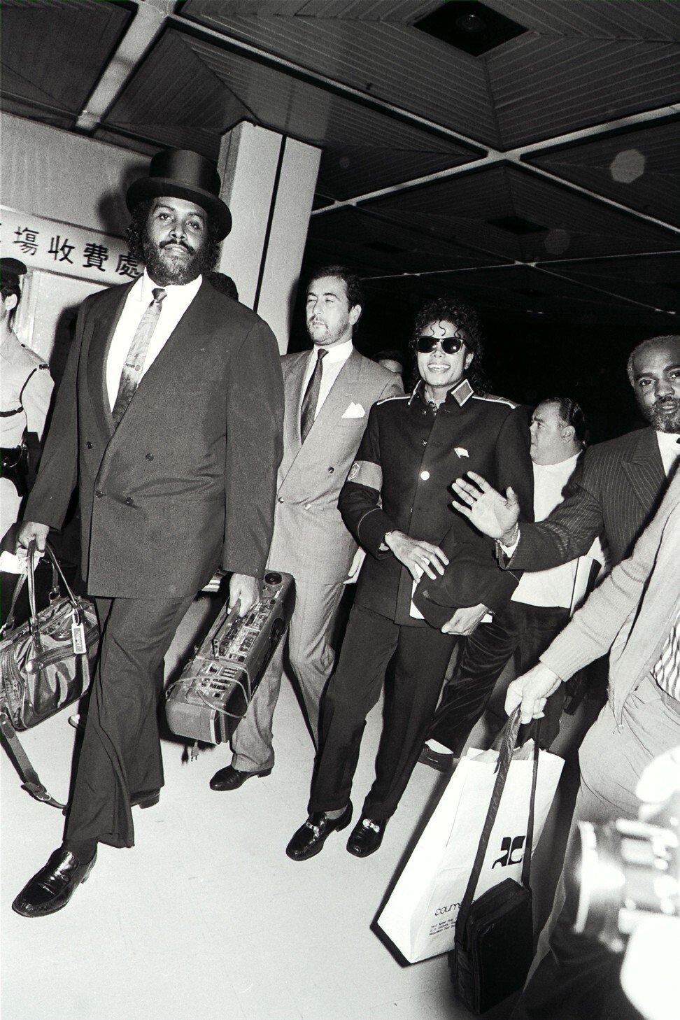 Michael Jackson with his entourage of bodyguards at Kai Tak Airport in November 1987. Photo: SCMP