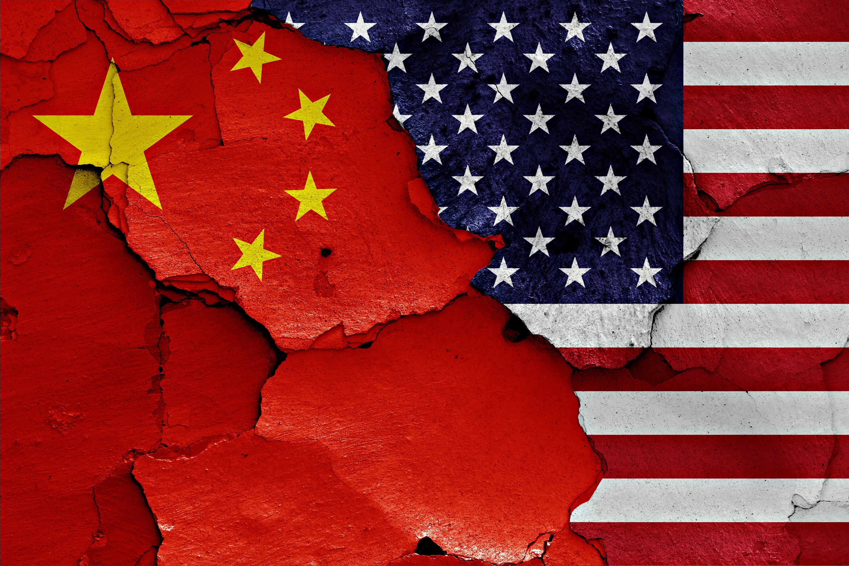 Flags of China and the US seen on a cracked background. Photo: Shutterstock